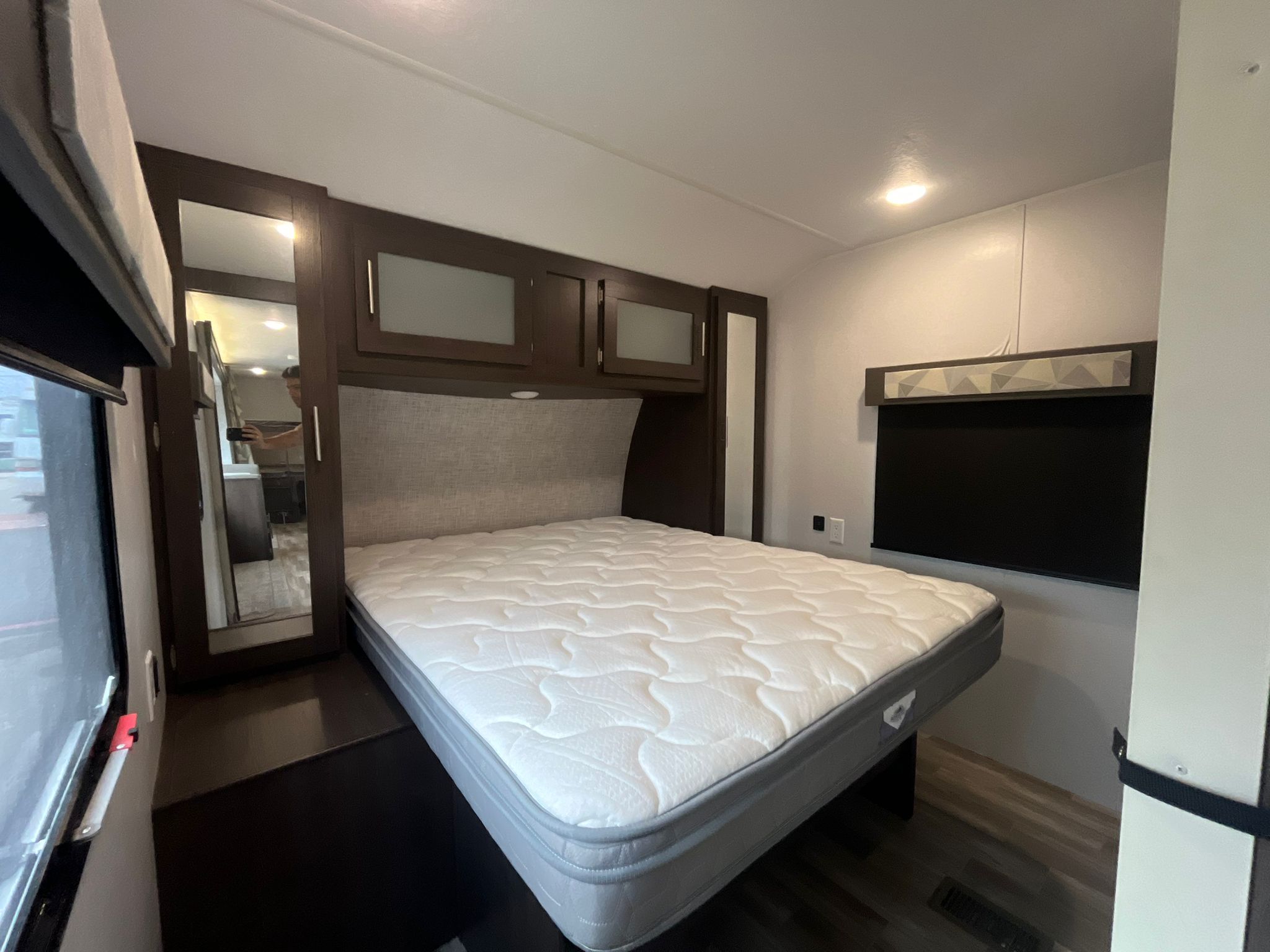 Spacious RV rental bedroom featuring a queen bed, overhead cabinets, full-length mirror, and TV area.. Forest River Salem 2020
