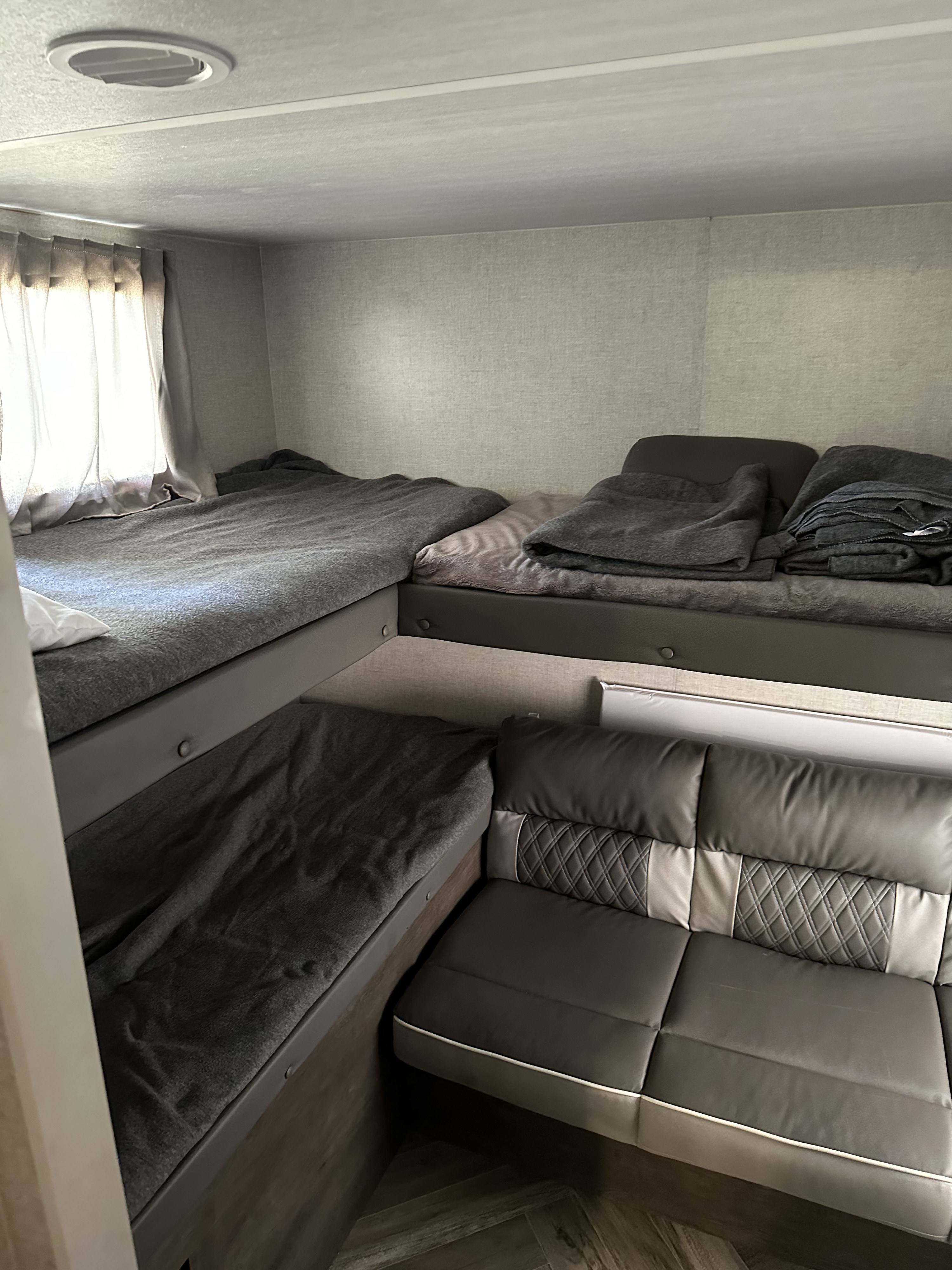 This RV rental bunkhouse features cozy gray bunk beds and comfortable quilted sofa seating.. Forest River Salem Cruise Lite 2021