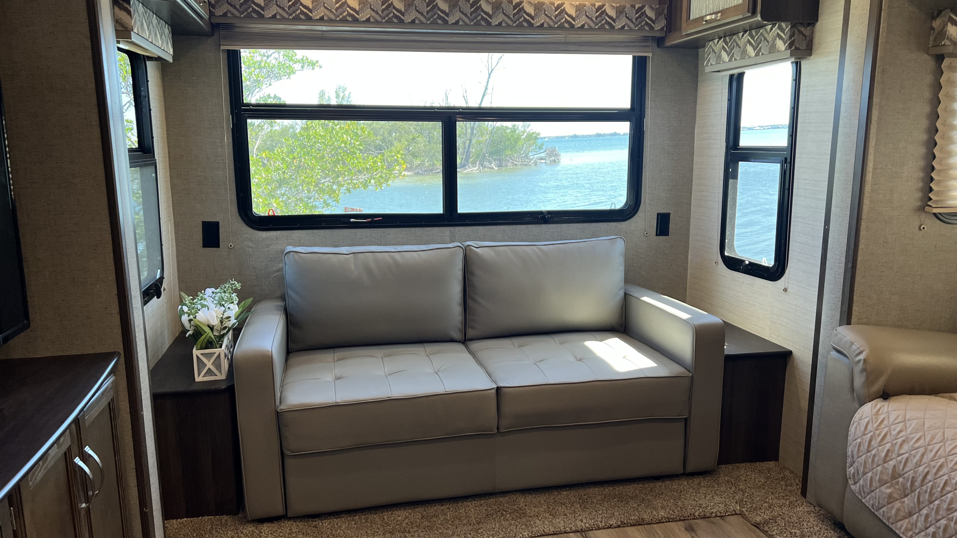 RV rental interior: comfy sofa, expansive windows offering a beautiful water view. Ideal living space for travel.. Keystone RV Bullet Premier 2018