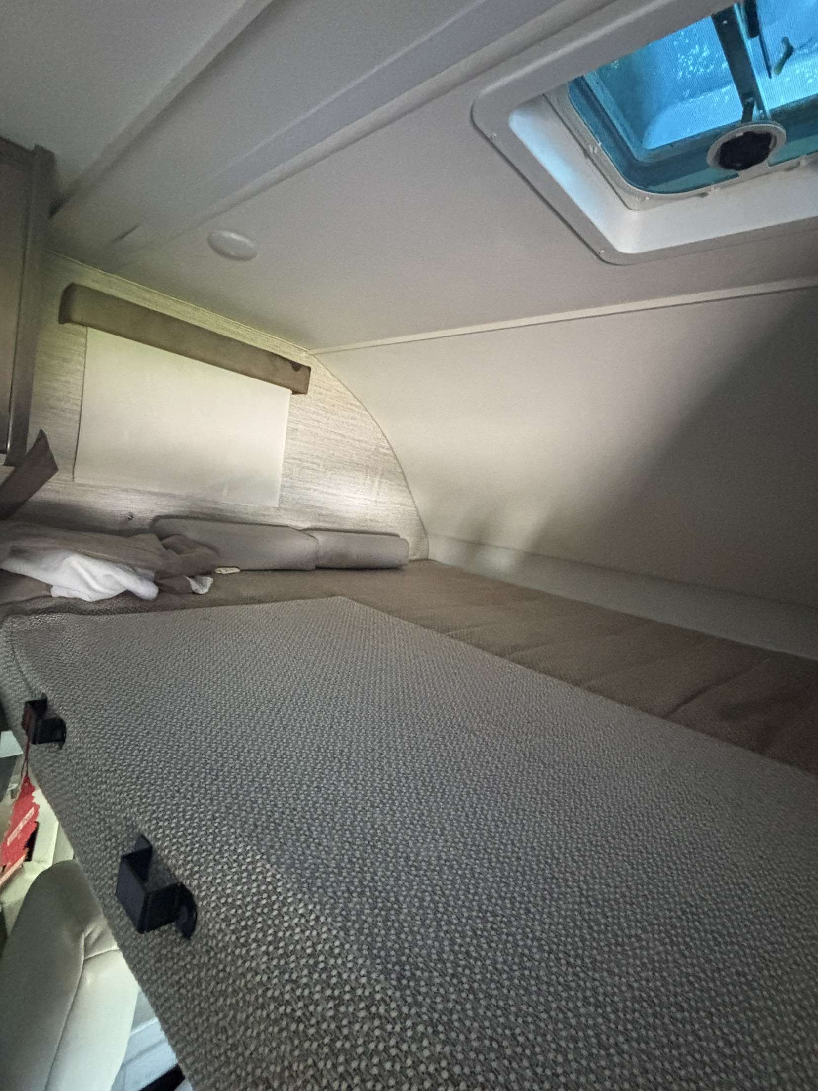 Inside an RV rental: a cozy cab-over bunk bed with textured mattress, pillows, and an overhead vent for air.. Winnebago Minnie Winnie 2022