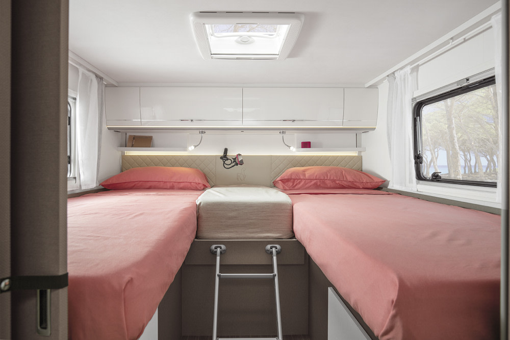 RV rental bedroom with two twin beds, overhead storage, reading lights, skylight, and a scenic window view.. Etrusco I7400SBC 2025