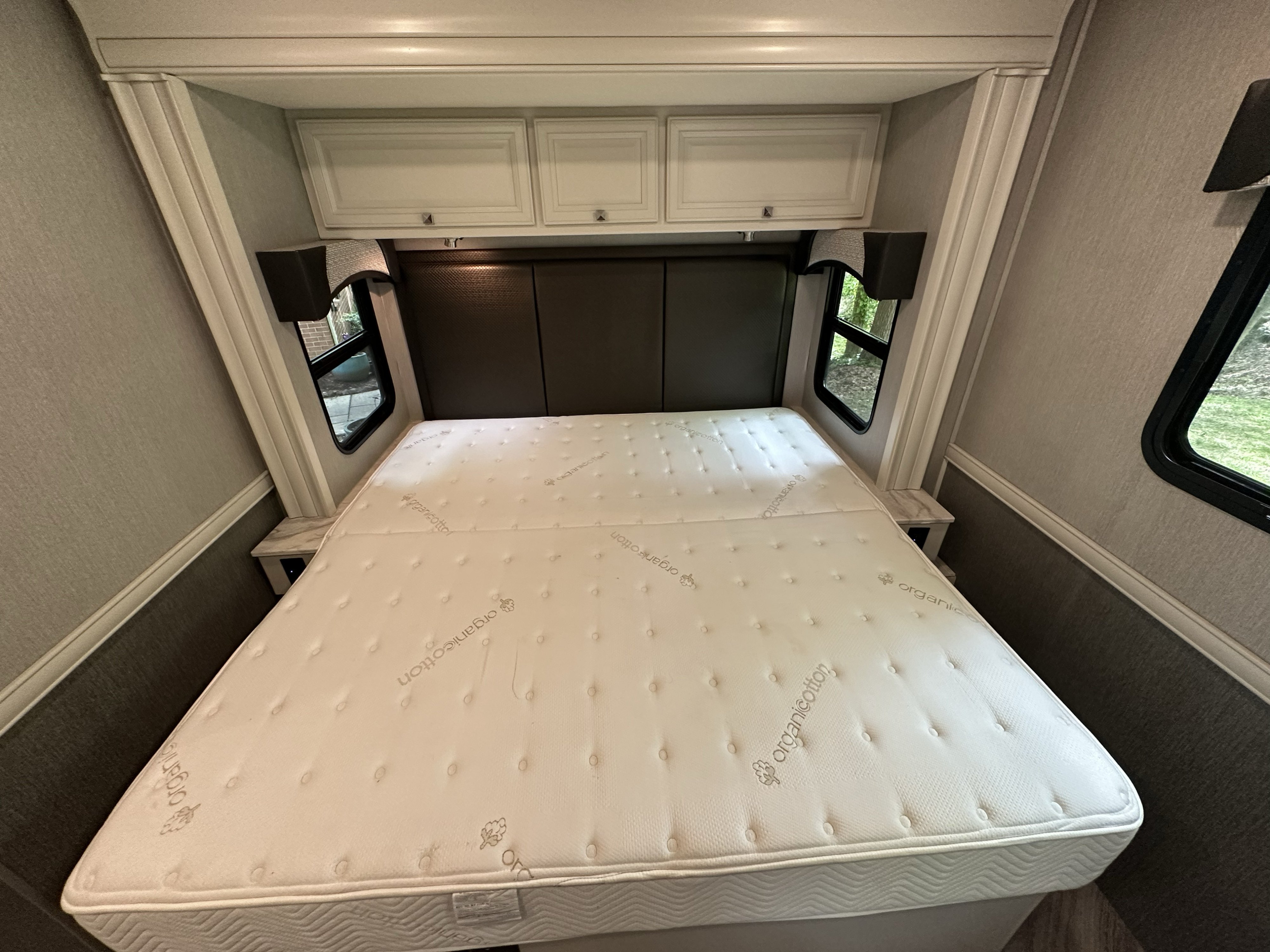 Spacious RV rental bedroom featuring a comfortable 'organic cotton' mattress, stylish headboard, and convenient overhead cabinets.. Fleetwood Fortis 2021