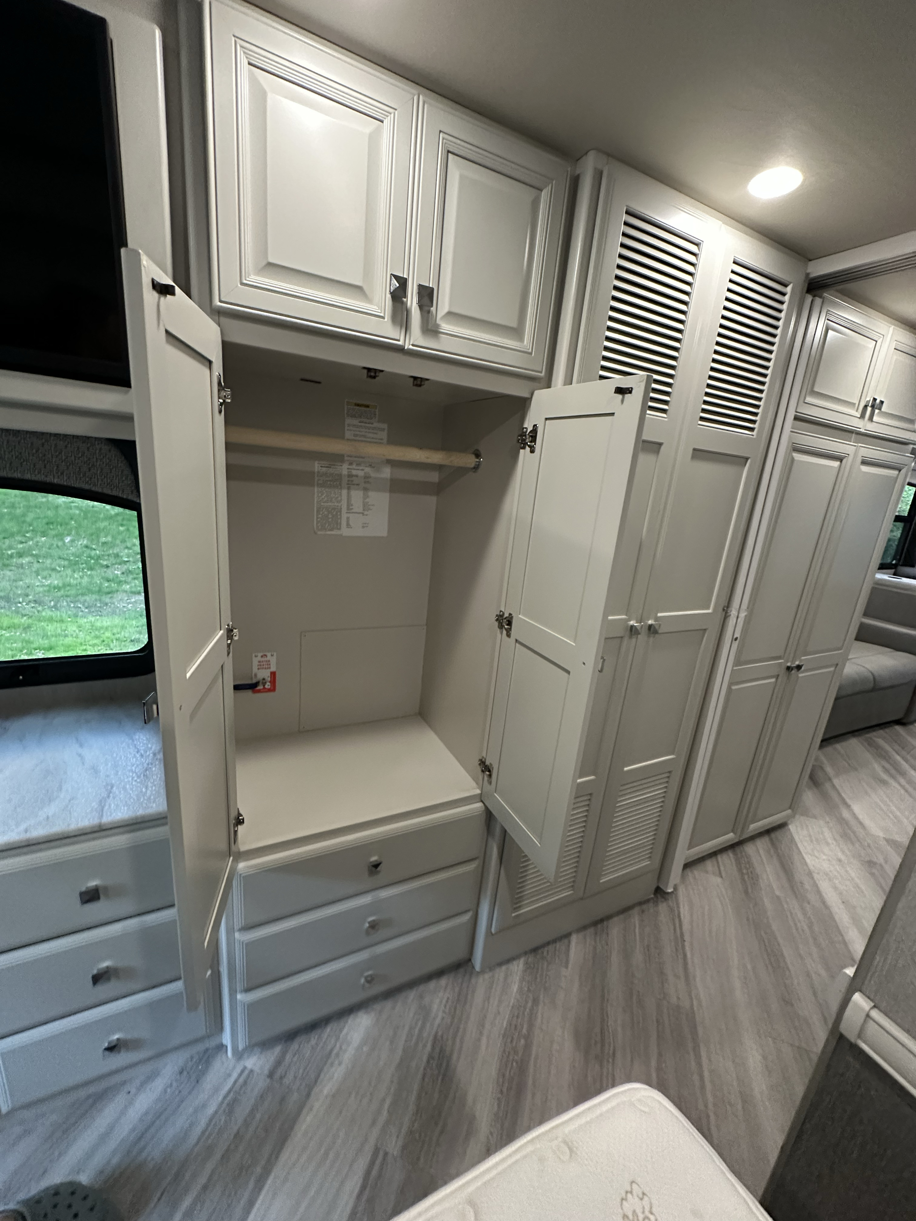 Spacious RV rental interior with light grey cabinets, hanging closet, drawers, and wood-look flooring, offering comfort.. Fleetwood Fortis 2021