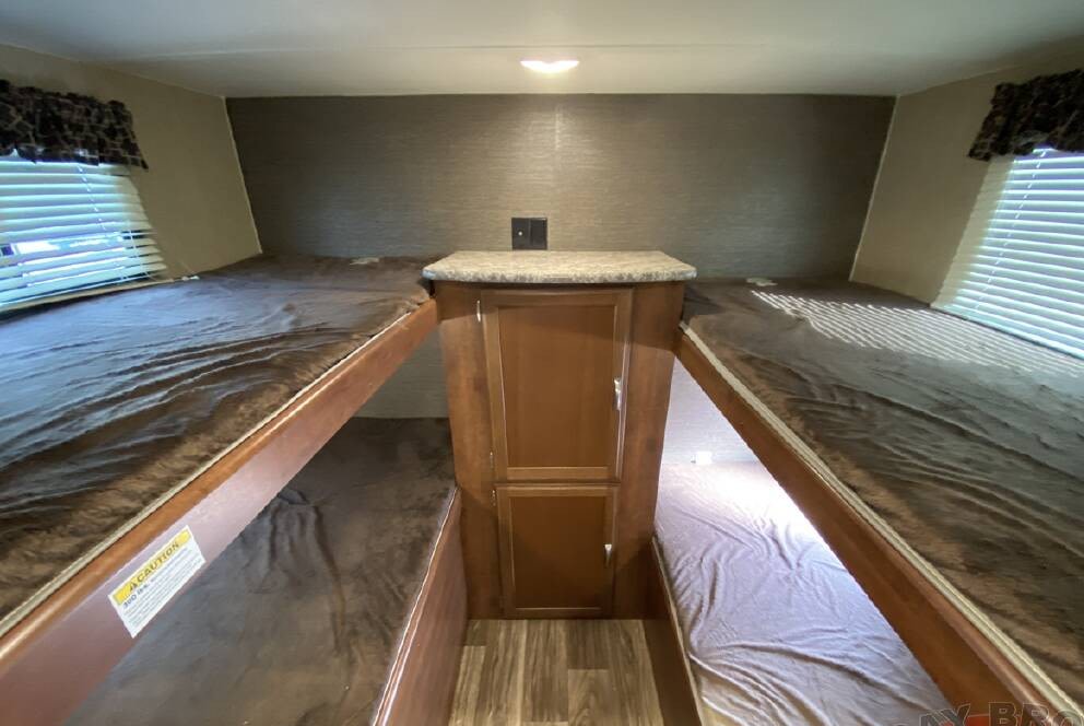 RV rental: Interior bunk room with four beds dressed in brown, a central storage unit, and window blinds.. Keystone RV Passport Grand Touring 2018