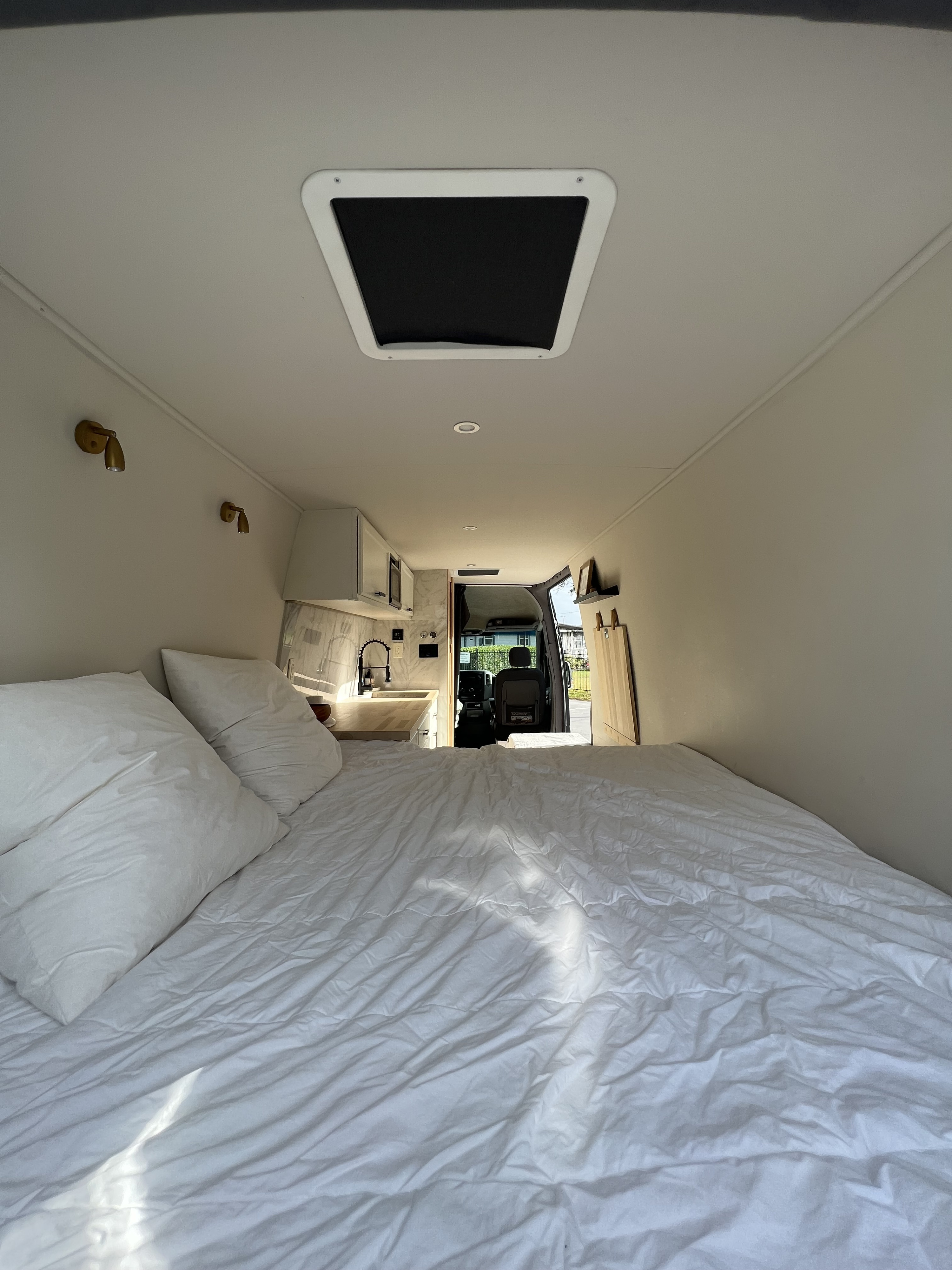 Inside a comfortable RV rental: white bedding, compact kitchen, and open driver's cabin. Ready for the road.. Dodge Sprinter 2008