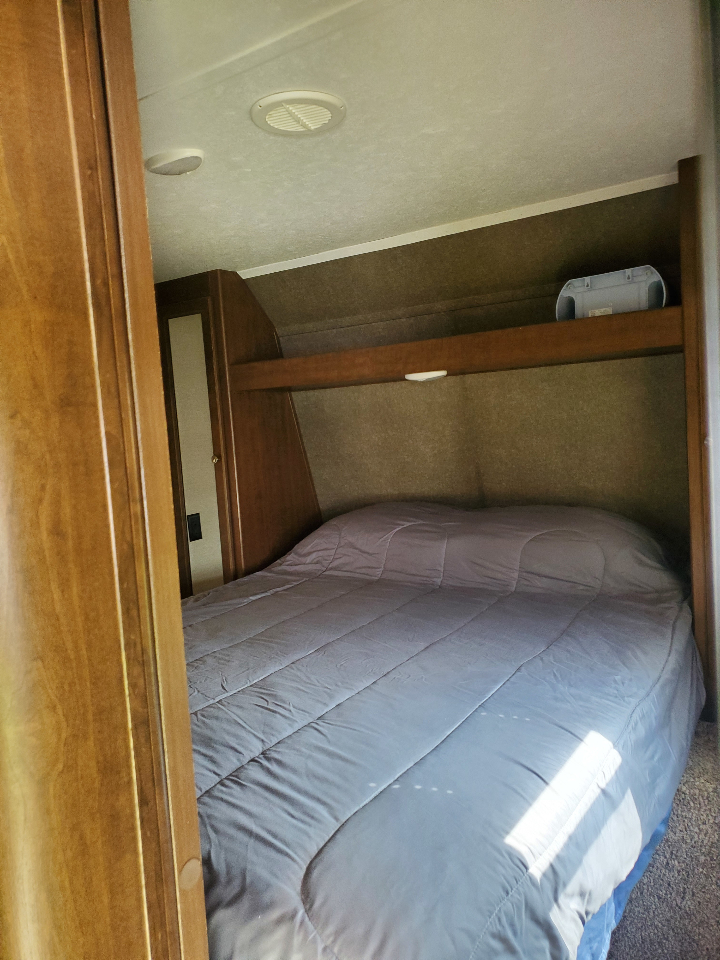 RV rental bedroom features a large bed, overhead storage, and a closet; sunlight highlights comfort for your travels.. Keystone RV Hideout 2018