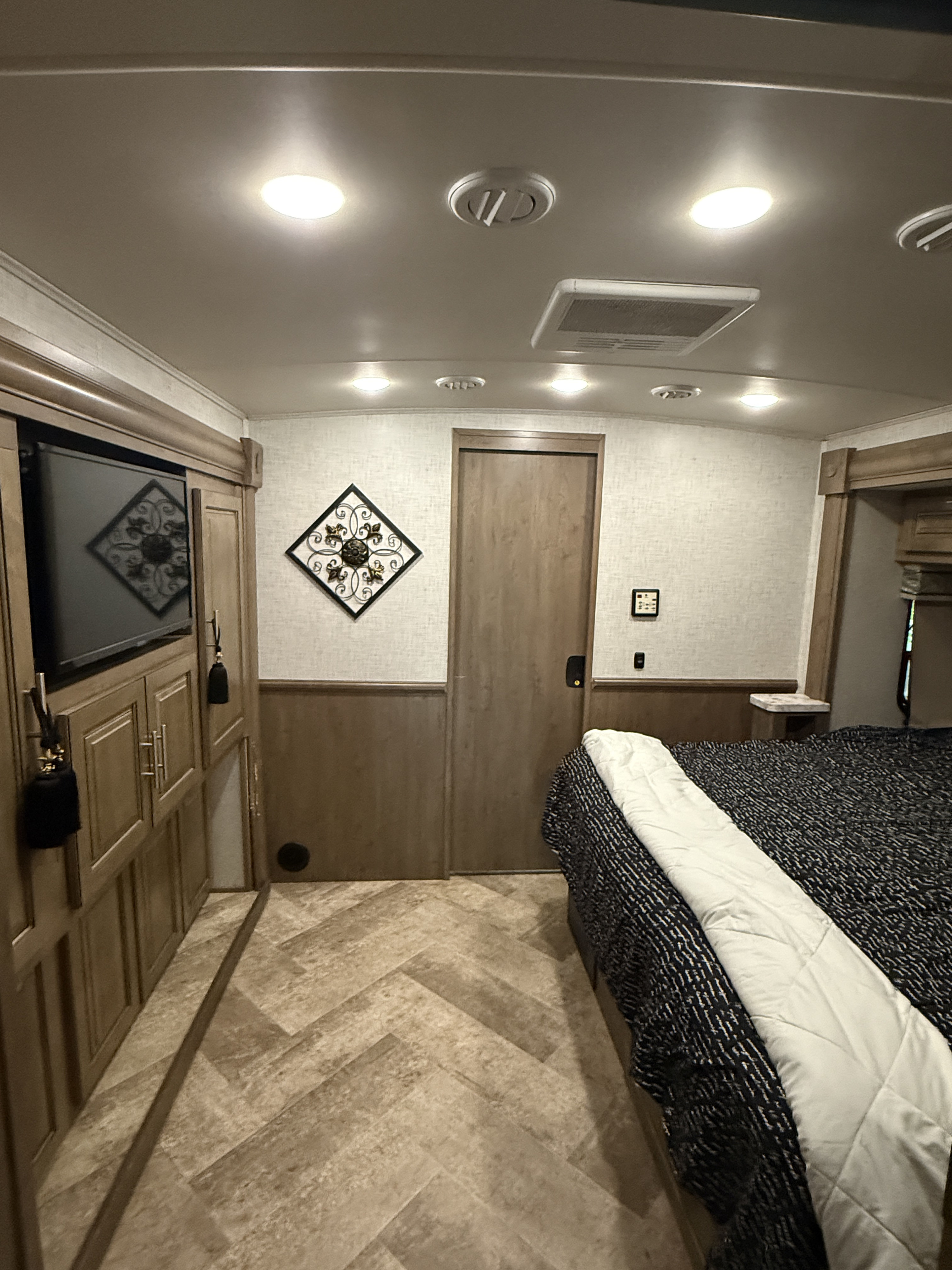 Inside a modern RV rental bedroom: bed, media center with TV, herringbone floor, and stylish wall decor. Comfortable for your trip.. Georgetown GT5 2020