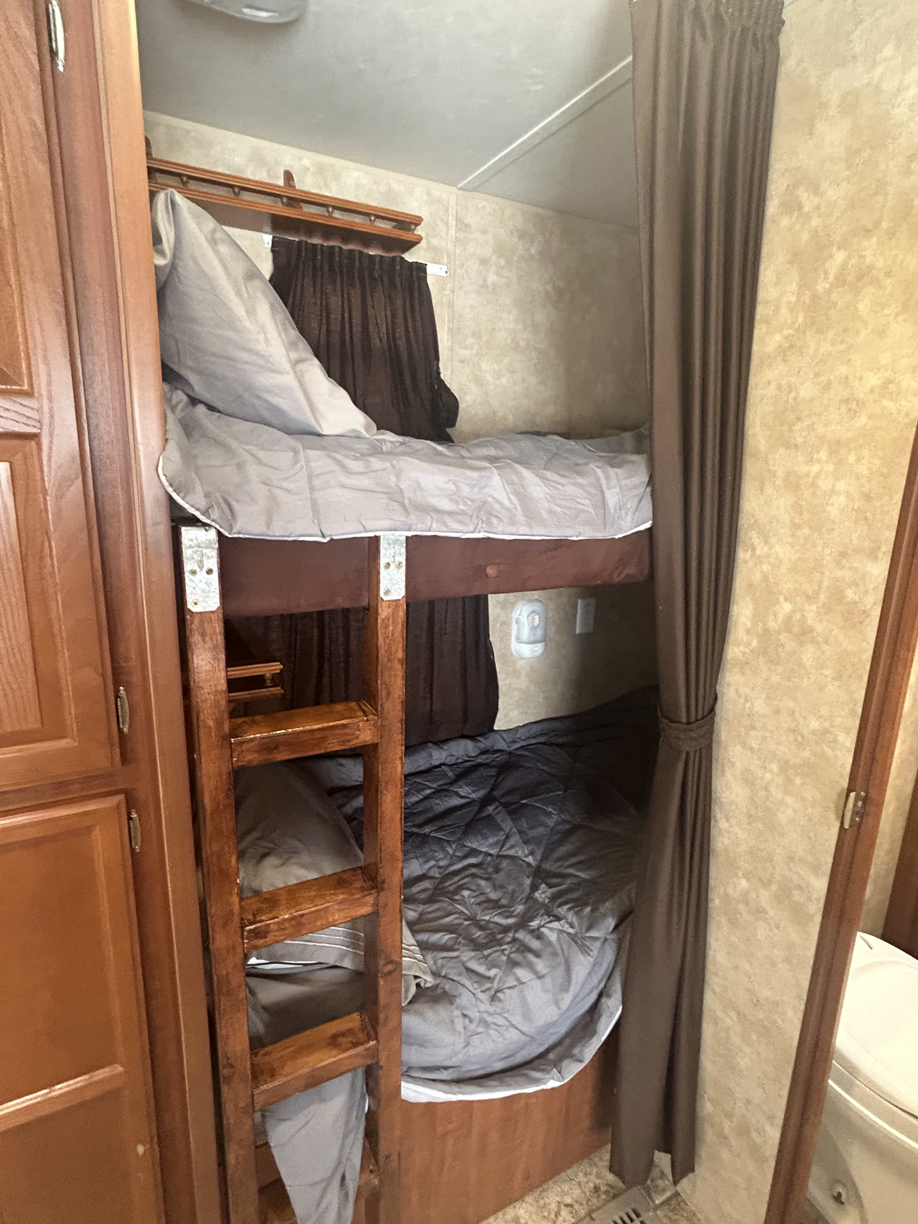 Cozy RV rental interior showcasing compact bunk beds, storage cabinets, and a dinette, designed for comfortable travel.. Jayco Jay Flight 2010