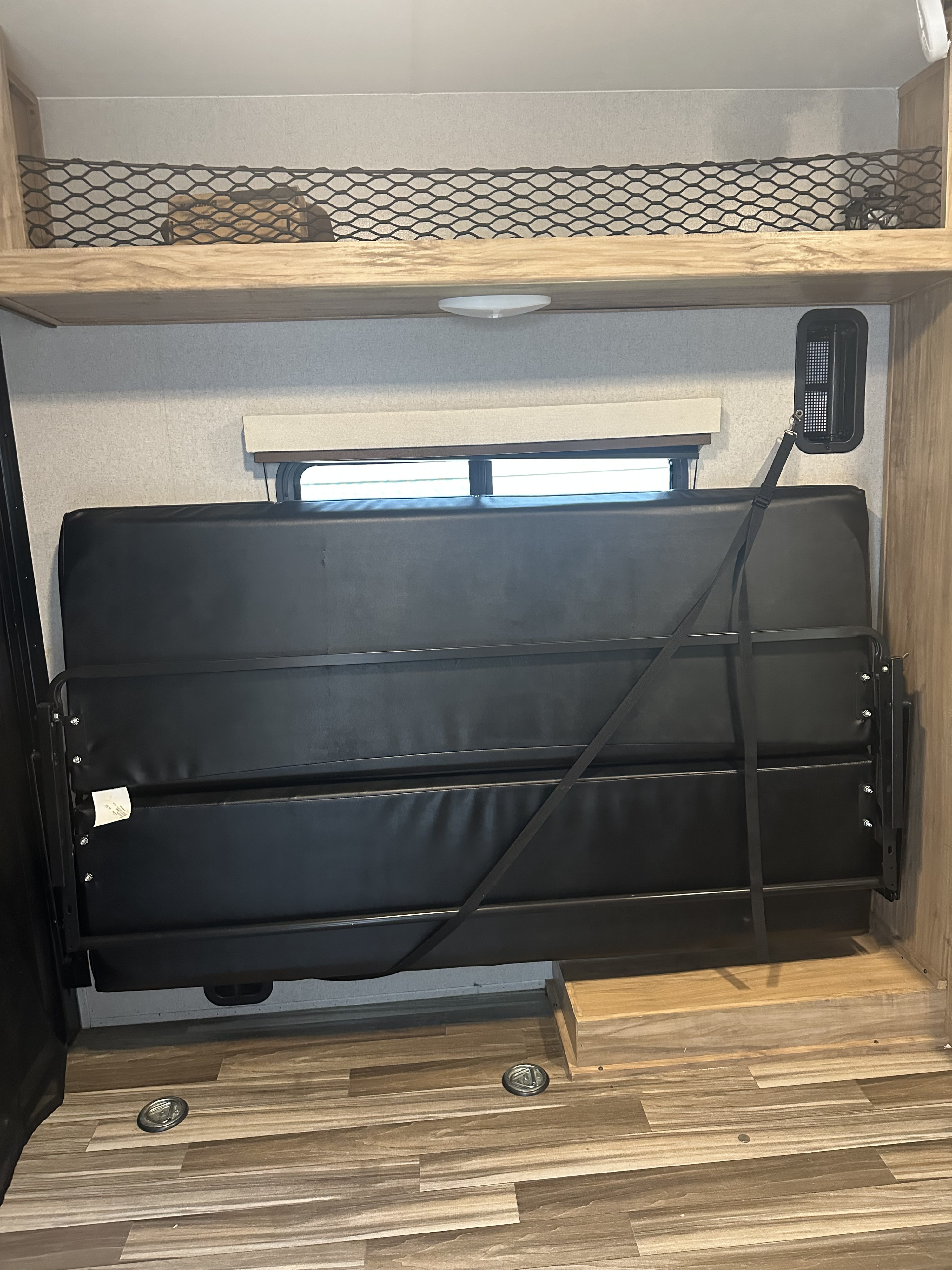 RV rental interior with a wall-mounted, secured bed/sofa, mesh overhead storage, and floor tie-downs.. Coachmen Freedom Express 2019