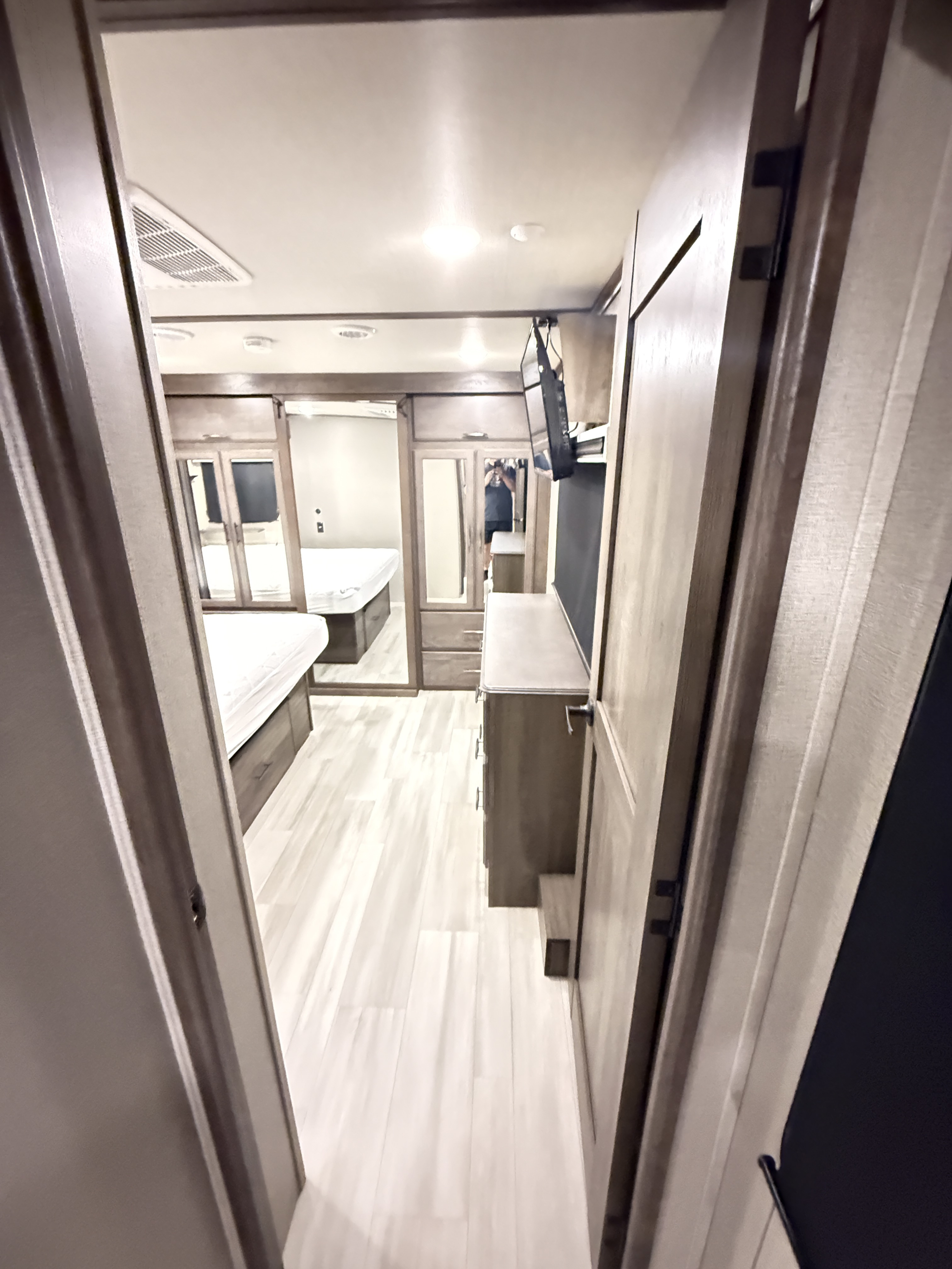 RV rental: View down a bright hallway into a bedroom with two beds, storage, and TV. Features light wood flooring.. Grand Design Solitude 2022