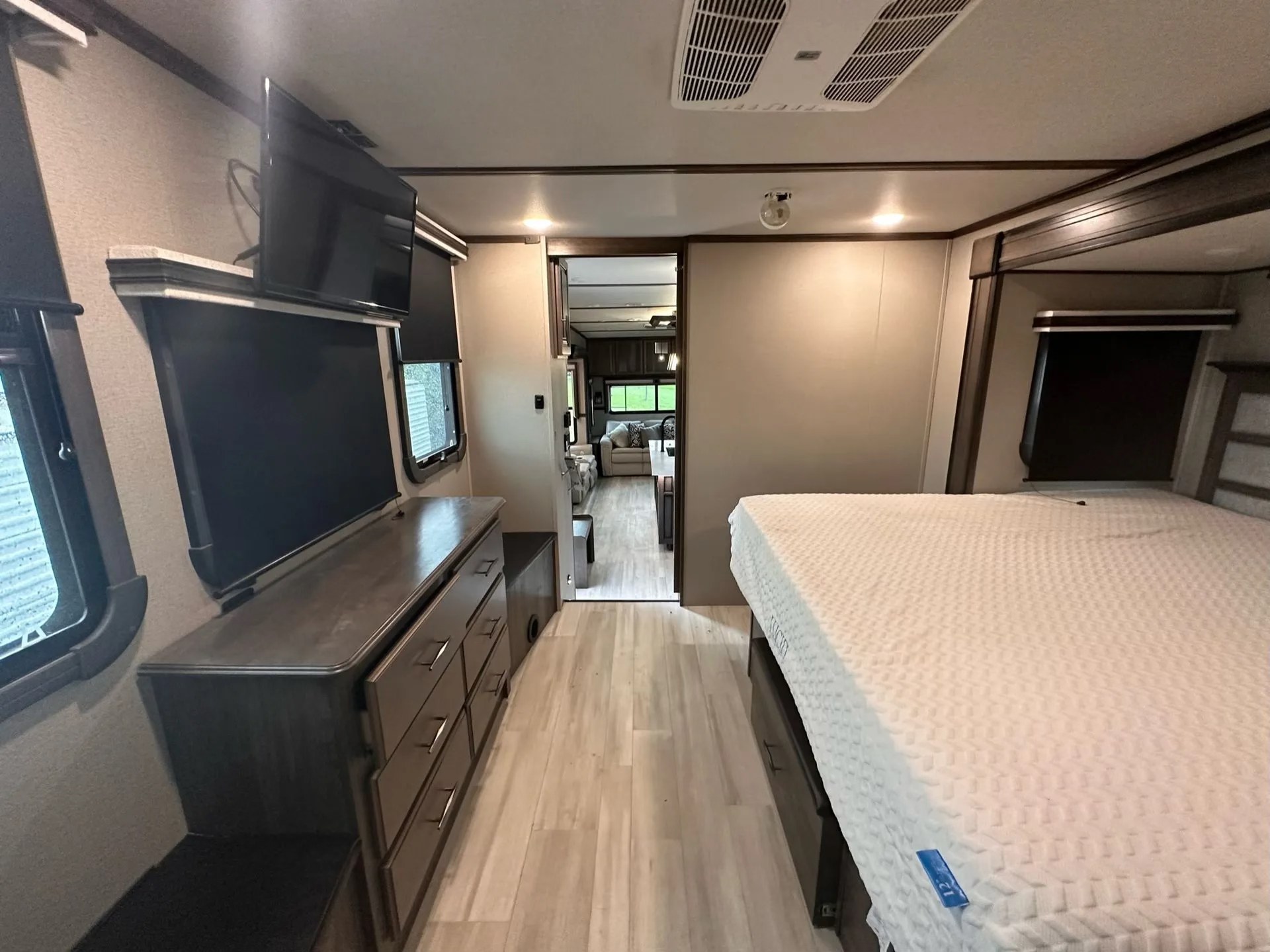 Explore this RV rental's spacious bedroom, featuring a comfy bed, TV, and dresser, opening to the main living area.. Grand Design Solitude 2021