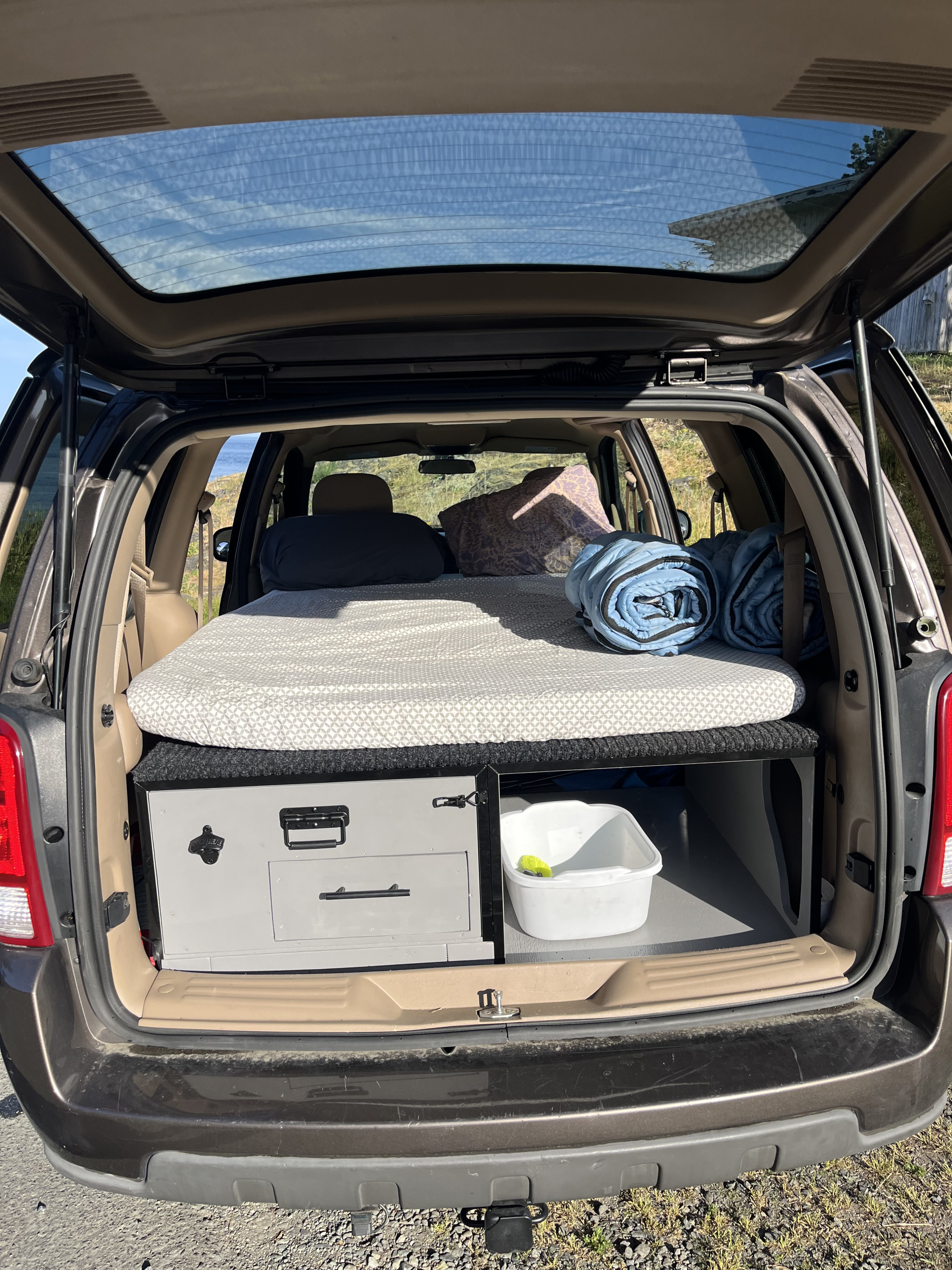 Back of an SUV converted to a micro-camper, showing a bed platform and storage drawers. Ideal for an RV rental trip.. Chevrolet Uplander 2009
