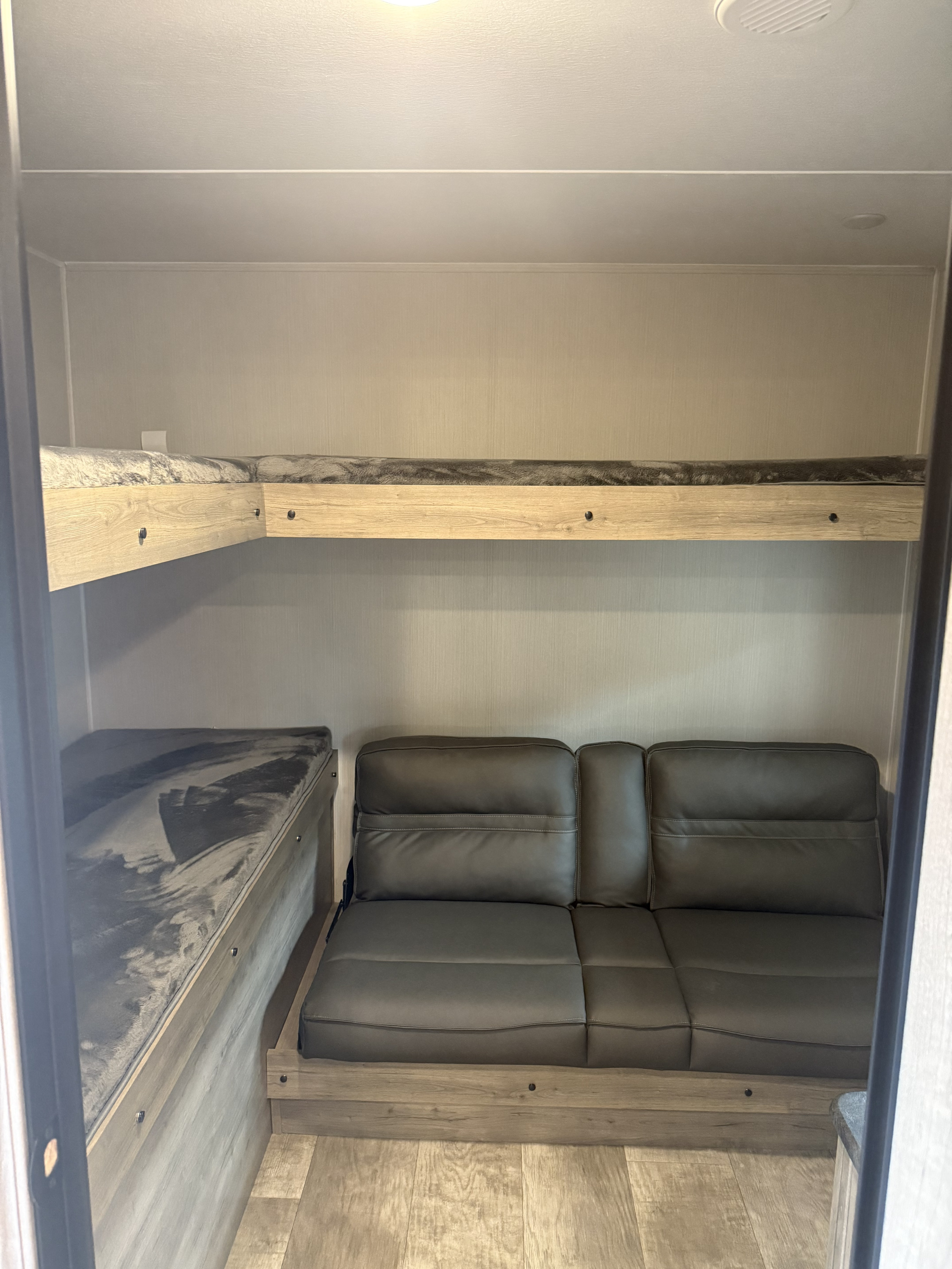 RV rental bunkhouse: Cozy interior with L-shaped upper bunk and convertible sofa for comfortable sleeping and living.. Forest River Palomino Puma 2025