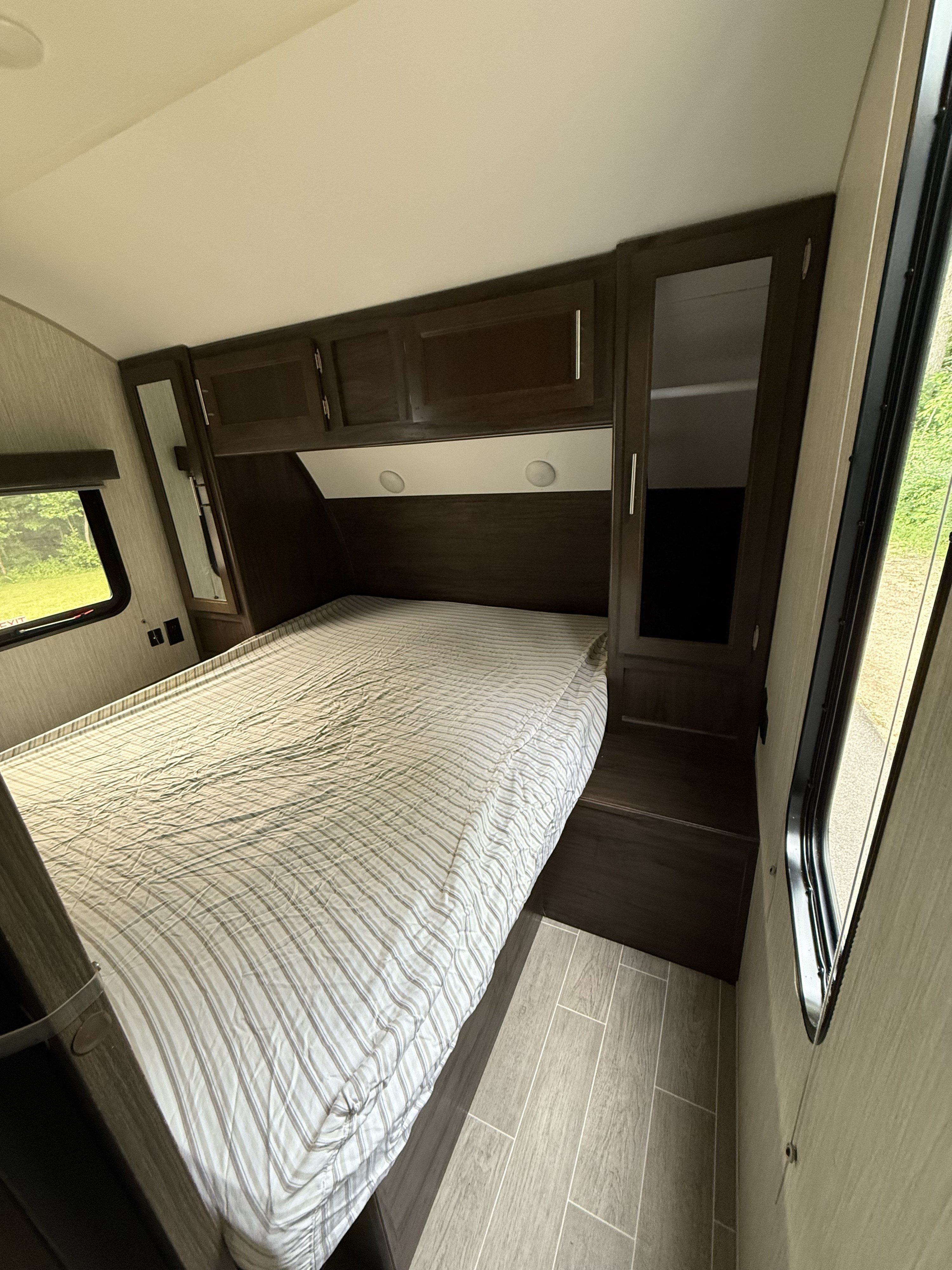 This RV rental bedroom offers a comfortable bed, overhead storage, and a scenic window view.. Forest River Cherokee 2020