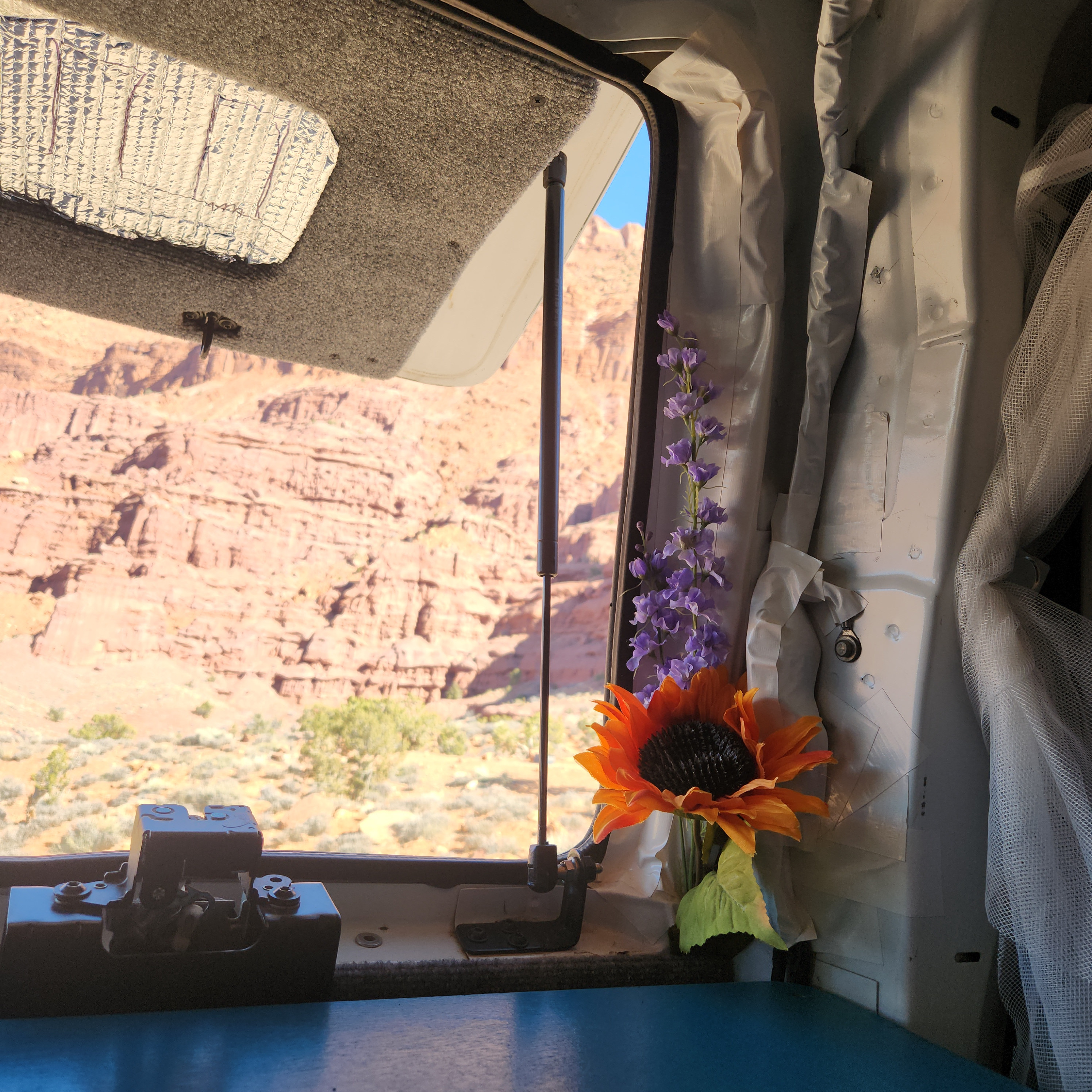 Scenic desert views from inside an RV rental. A window opens to red rock formations; flowers adorn the cozy interior.. Chevrolet Express 1500 AWD 2014