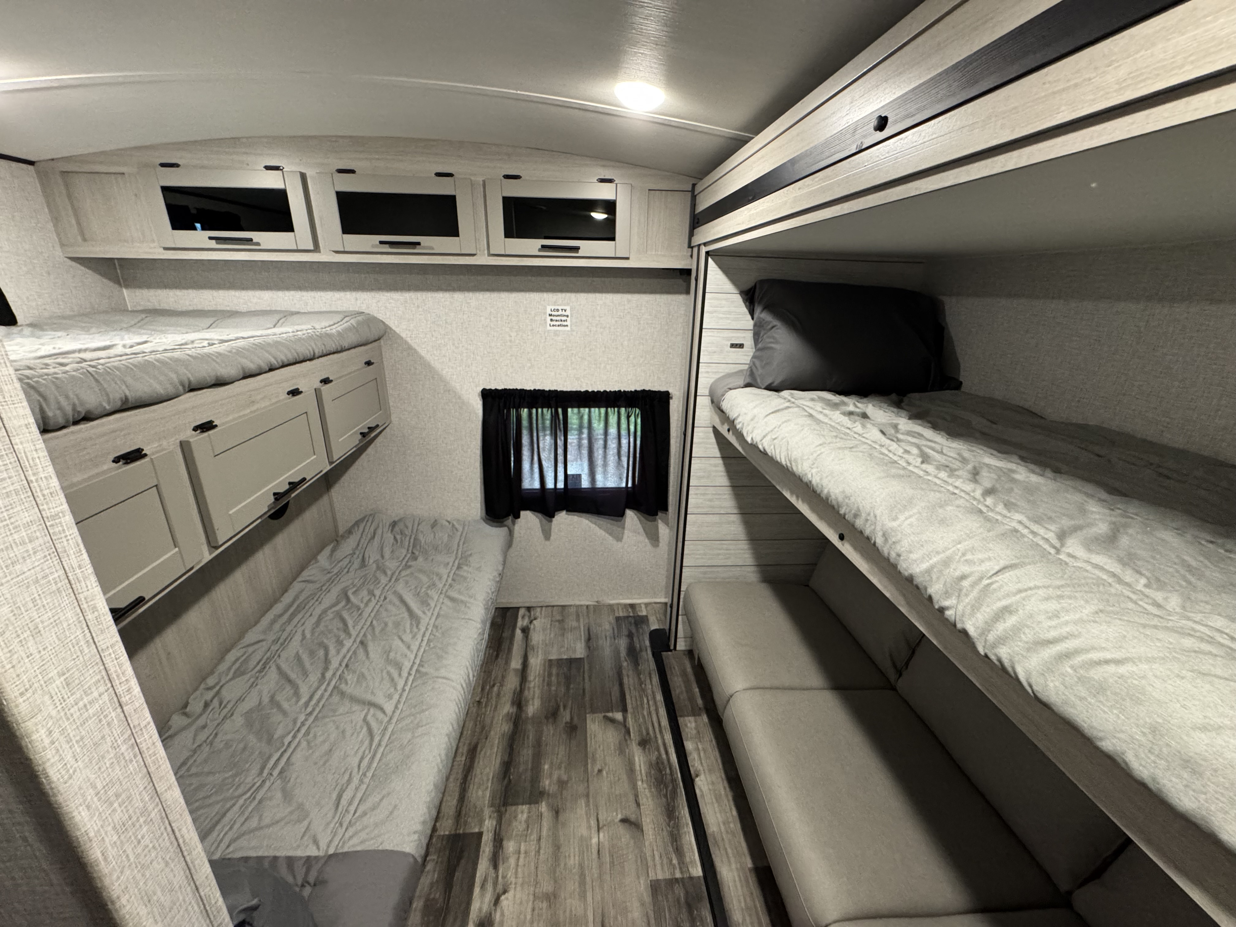 RV rental interior featuring cozy bunk beds with ample storage, a window, and wood-look flooring for comfort.. Crossroads RV Sunset Trail 2024