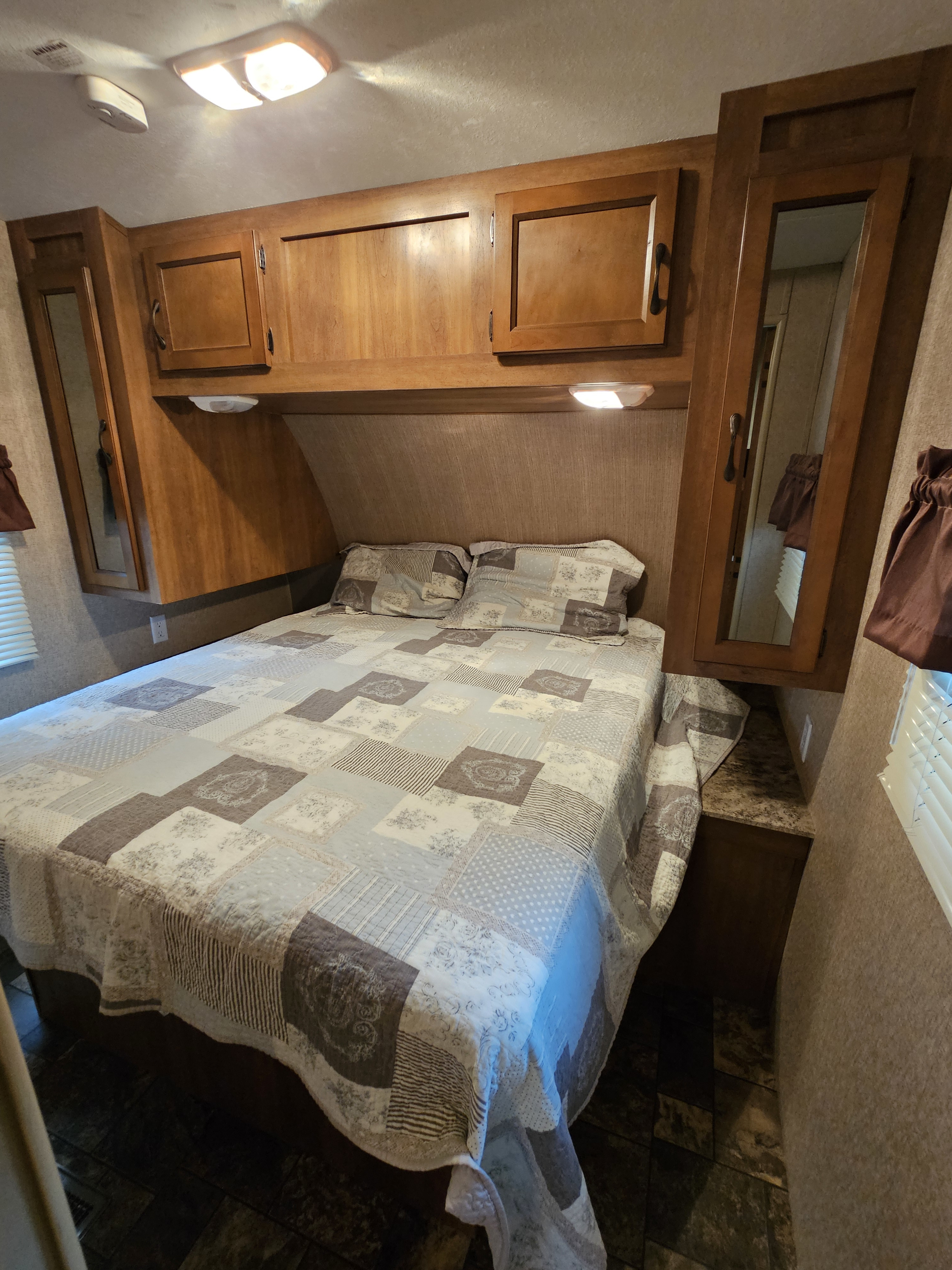 Cozy RV rental bedroom with queen bed, patchwork quilt, mirrored wardrobes, overhead cabinets, & lighting.. Forest River Coachmen Catalina 2014