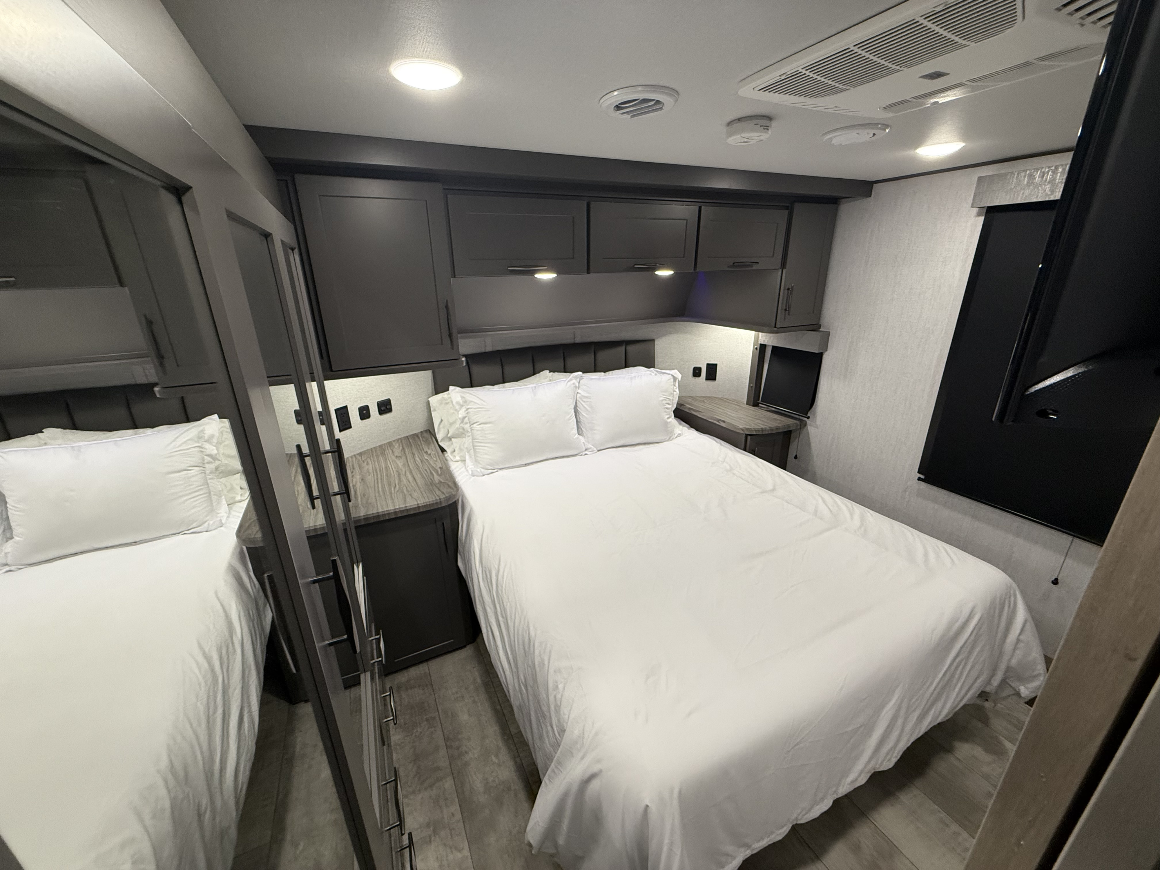 Comfortable RV rental bedroom featuring a white bed, ample overhead storage, and modern amenities like lighting and a TV.. Grand Design Grand Design Fifth Wheel 2024