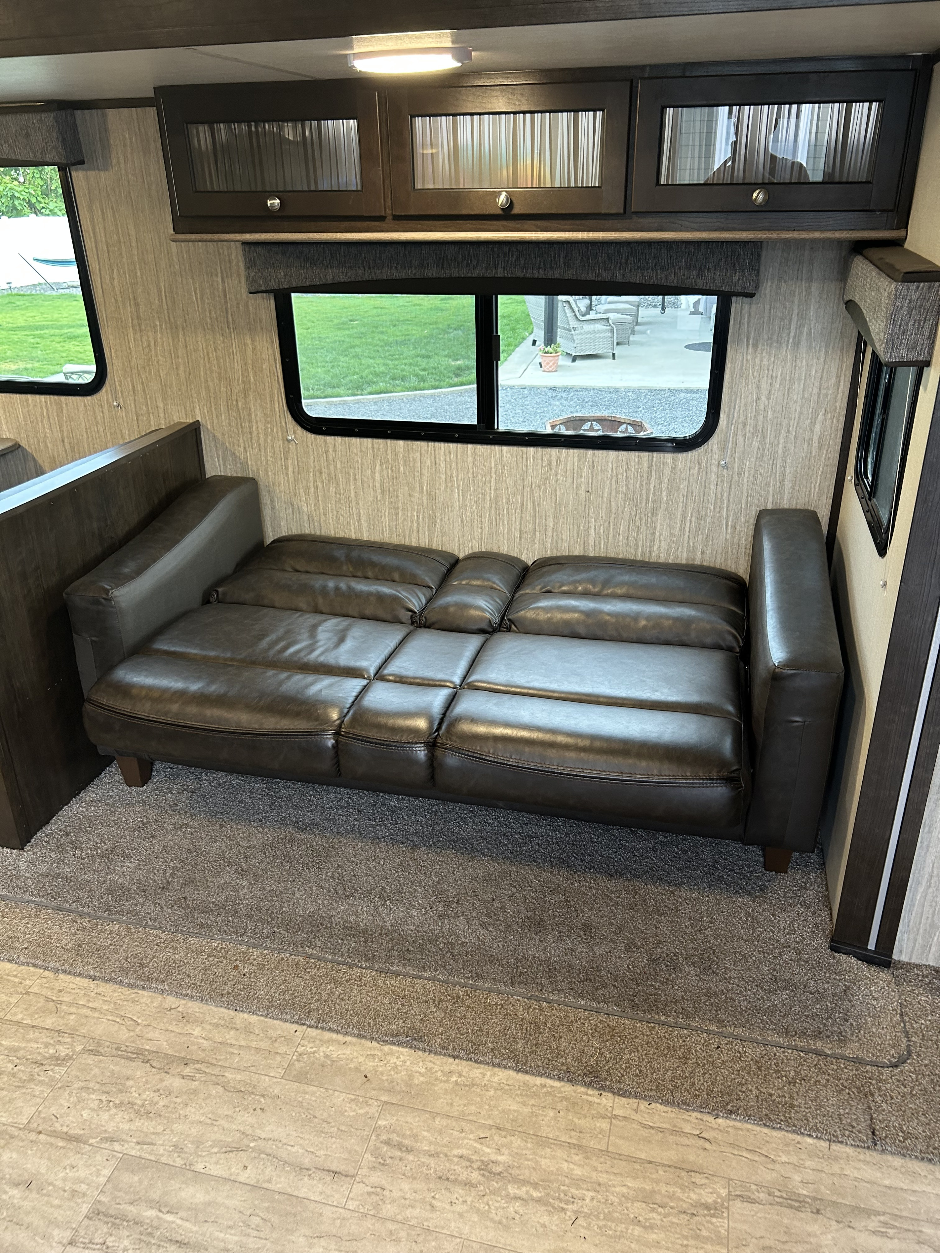 Spacious RV rental interior features a dark brown convertible sofa bed, ample windows, and overhead cabinets.. Cruiser RV Shadow Cruiser 2018