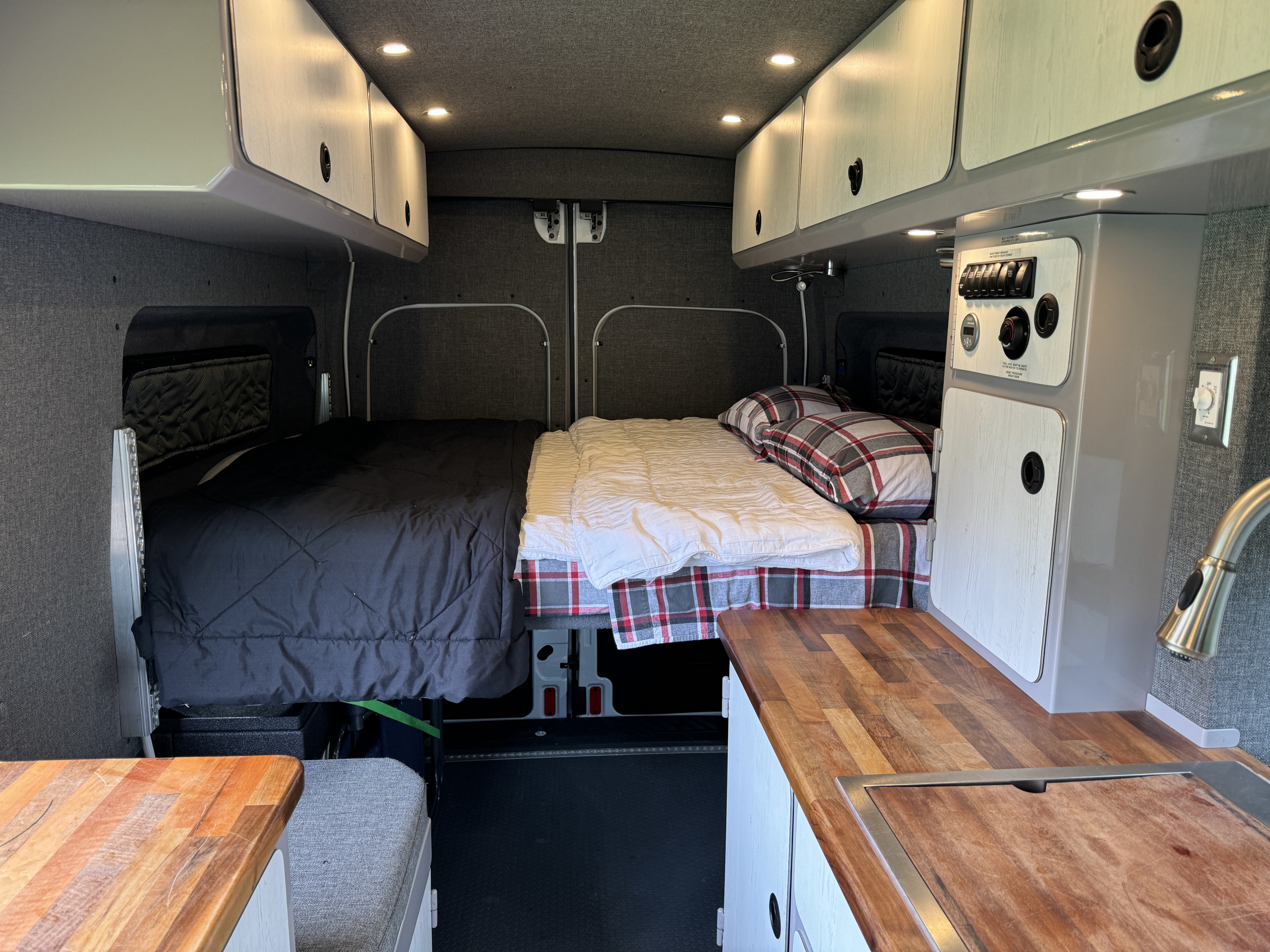 Spacious RV rental interior featuring twin sleeping areas, overhead storage, and a functional kitchen counter.. Ford Transit 2020