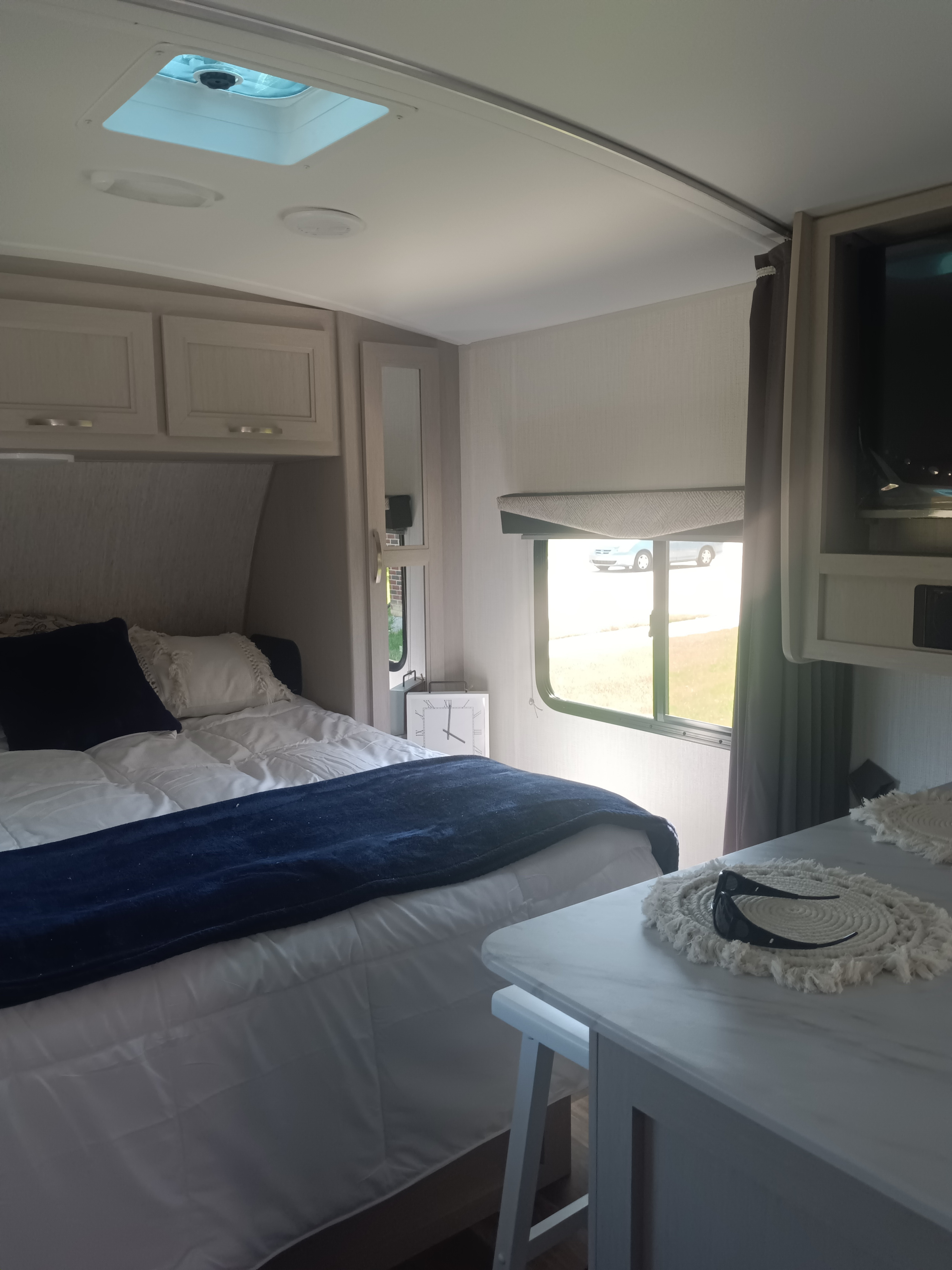 Cozy RV rental bedroom with modern decor, comfortable bed, overhead storage, and natural light.. Cruiser RV Shadow Cruiser 225RBS 2025