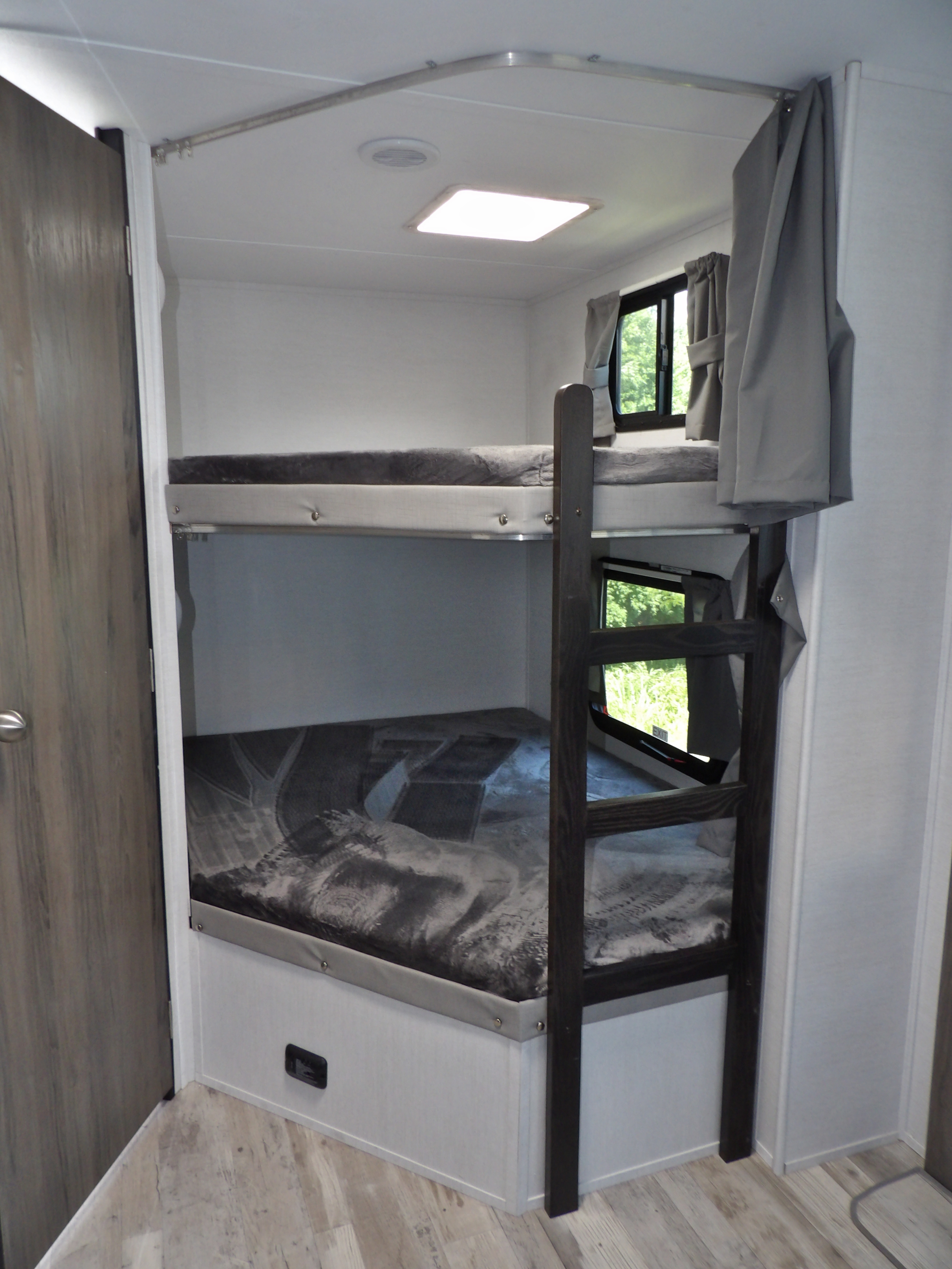 View inside an RV rental features two cozy bunk beds with windows, curtains, and a sturdy wooden ladder.. Other Envision 28BBS 2025