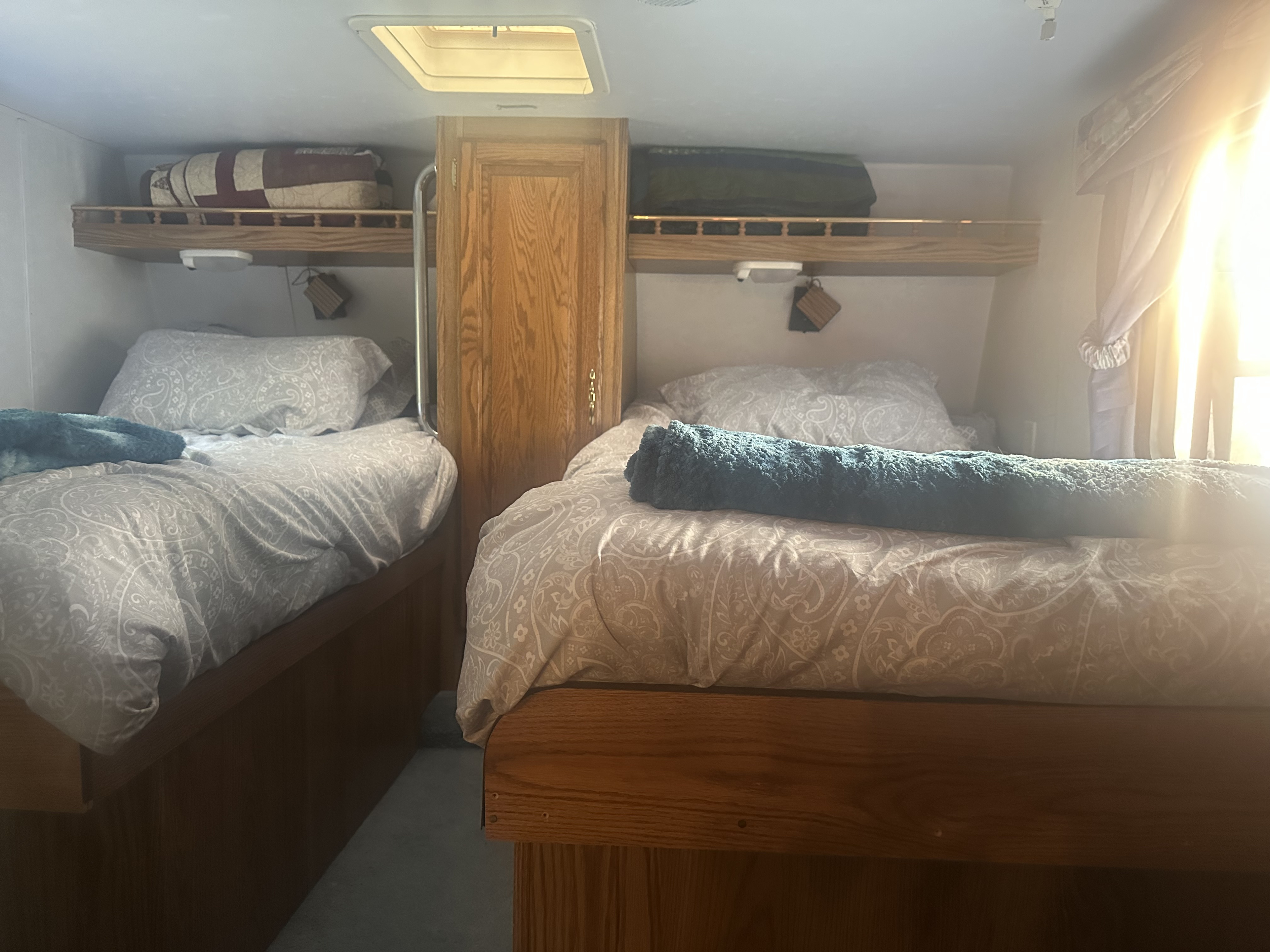 Two comfortable twin beds with patterned bedding inside an RV rental, illuminated by sunlight.. Wildwood 32qbss 5W 24RLS 1999