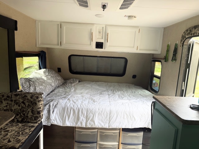Cozy RV rental interior: a bright bedroom with a bed, white cabinets, and dining area. Ideal for travel.. KZ 4EZTK1913J4070254 2017
