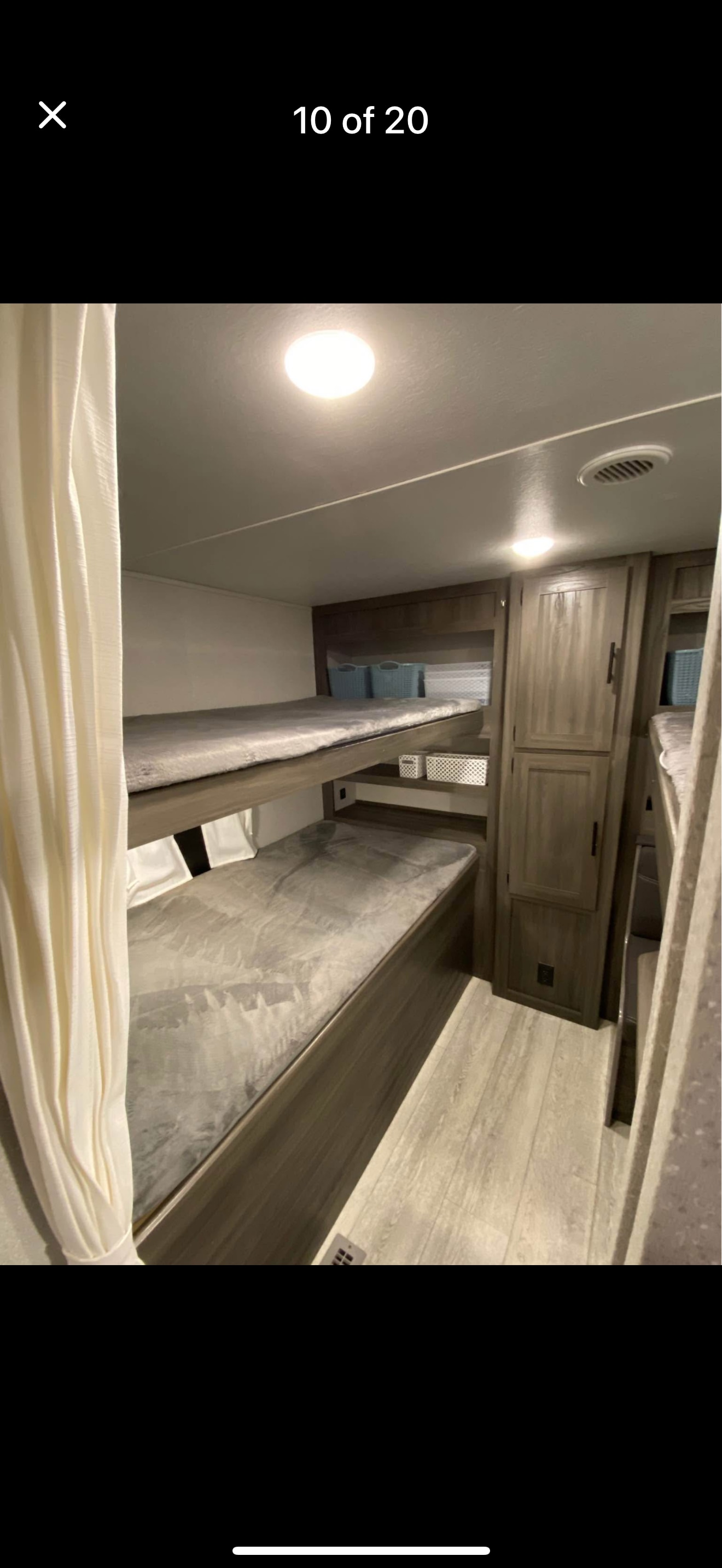 Inside an RV rental: a cozy bunk bed sleeping area with two beds, wooden accents, and soft overhead lighting.. Forest River Shasta 2021