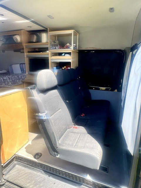 Inside an RV rental: custom storage shelves, an integrated TV, comfortable seating, and a rear bed area.. Mercedez Sprinter 2014