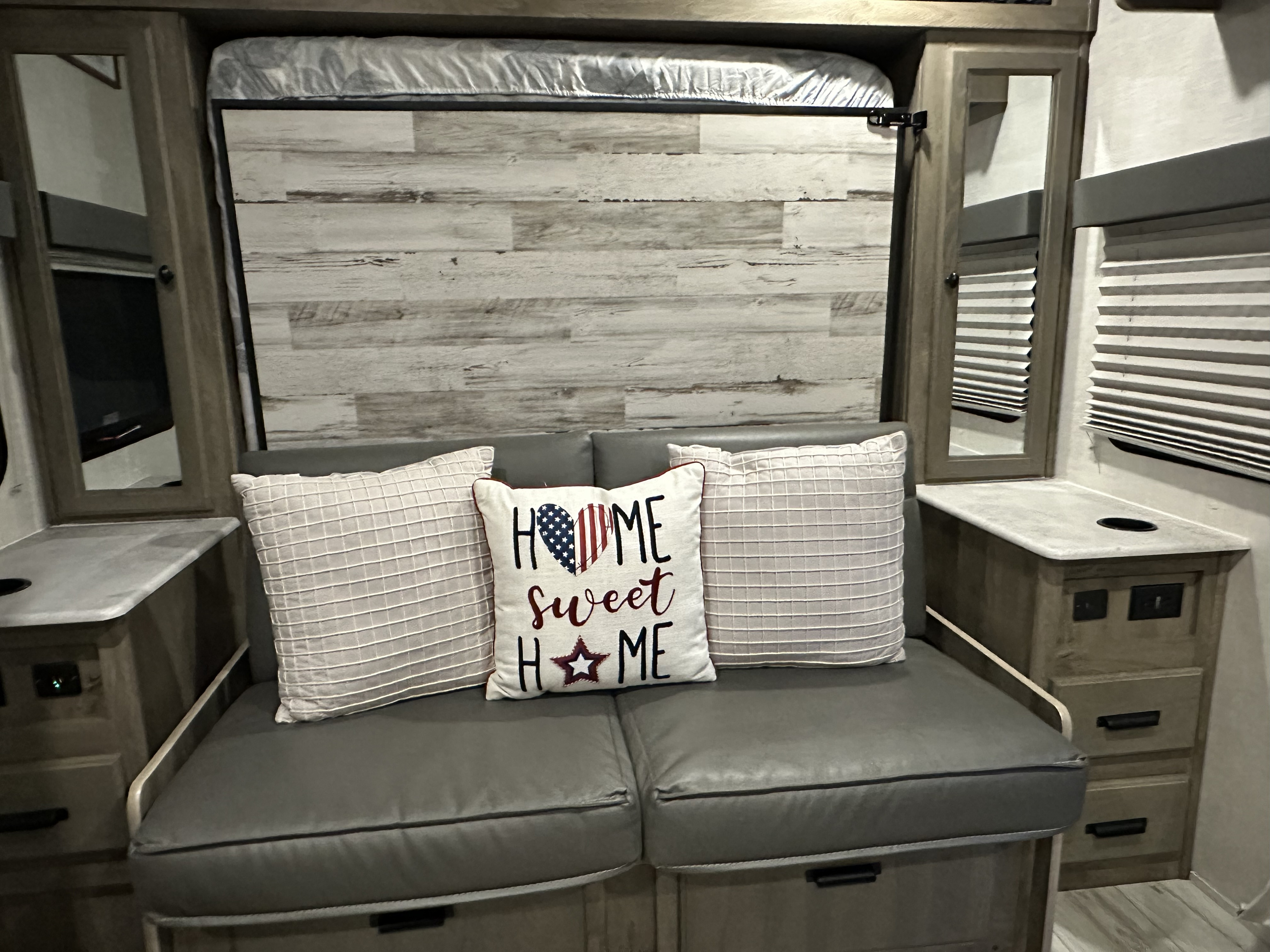 Versatile RV rental living space: a cozy sofa, pull-down bed, wood-look wall, and practical built-ins.. Forest River Surveyor Legend 2022