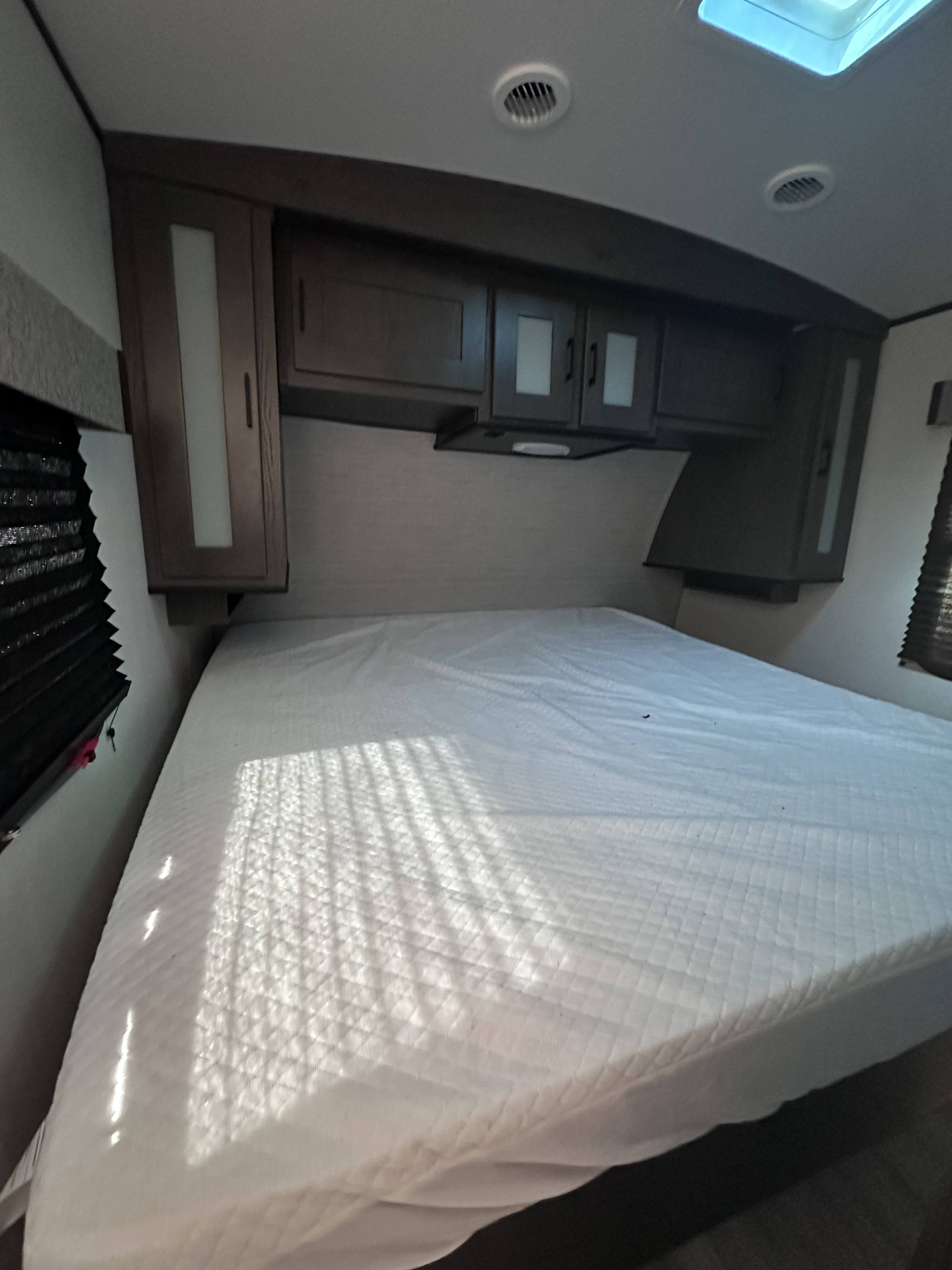 Inside an RV rental: Compact bedroom featuring a large bed, overhead storage, and sunlit window blinds.. MPG Cruiser RV ultra light 2500 2021