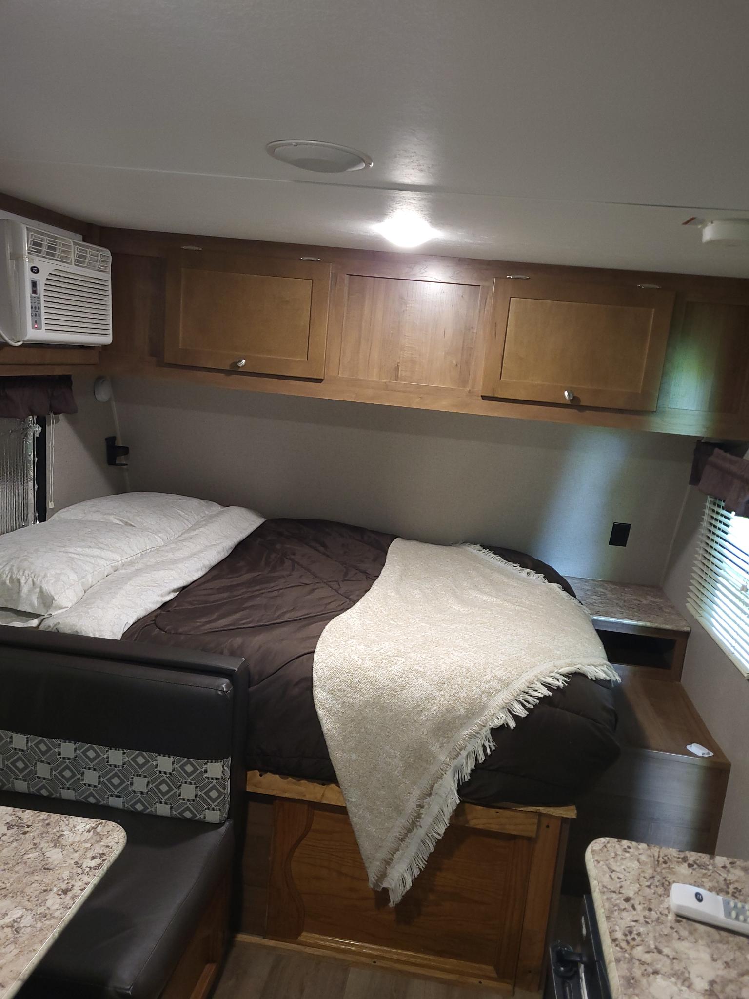 Cozy rv rental interior featuring a bed, air conditioner, overhead cabinets, and a dinette area.. Aspen Trail Aspen Trail Trailer 2018