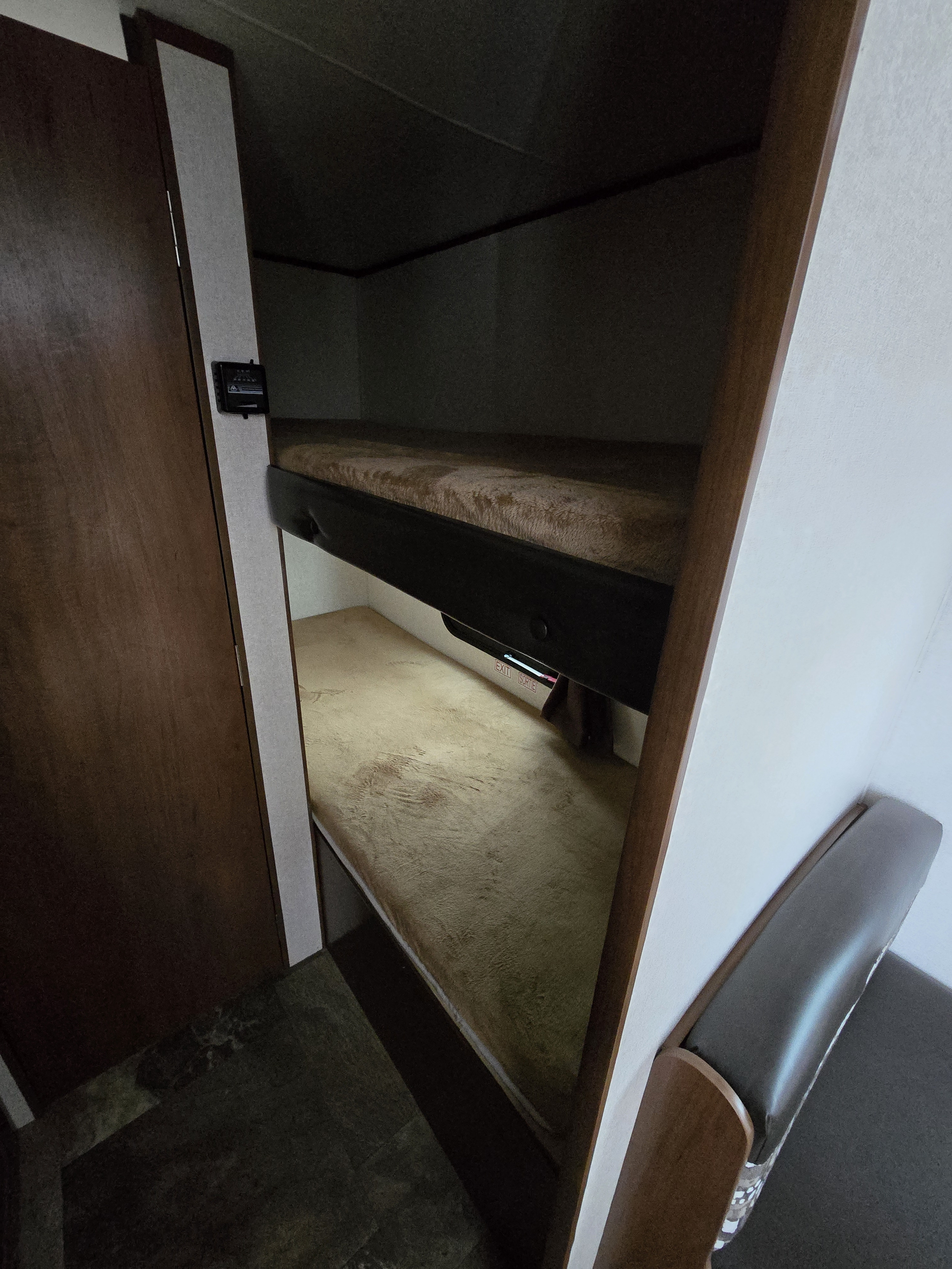 RV rental interior: cozy bunk beds, emergency exit light, wood door, & seating. A compact and functional sleeping area.. Jayco Jay Flight SLX 2017