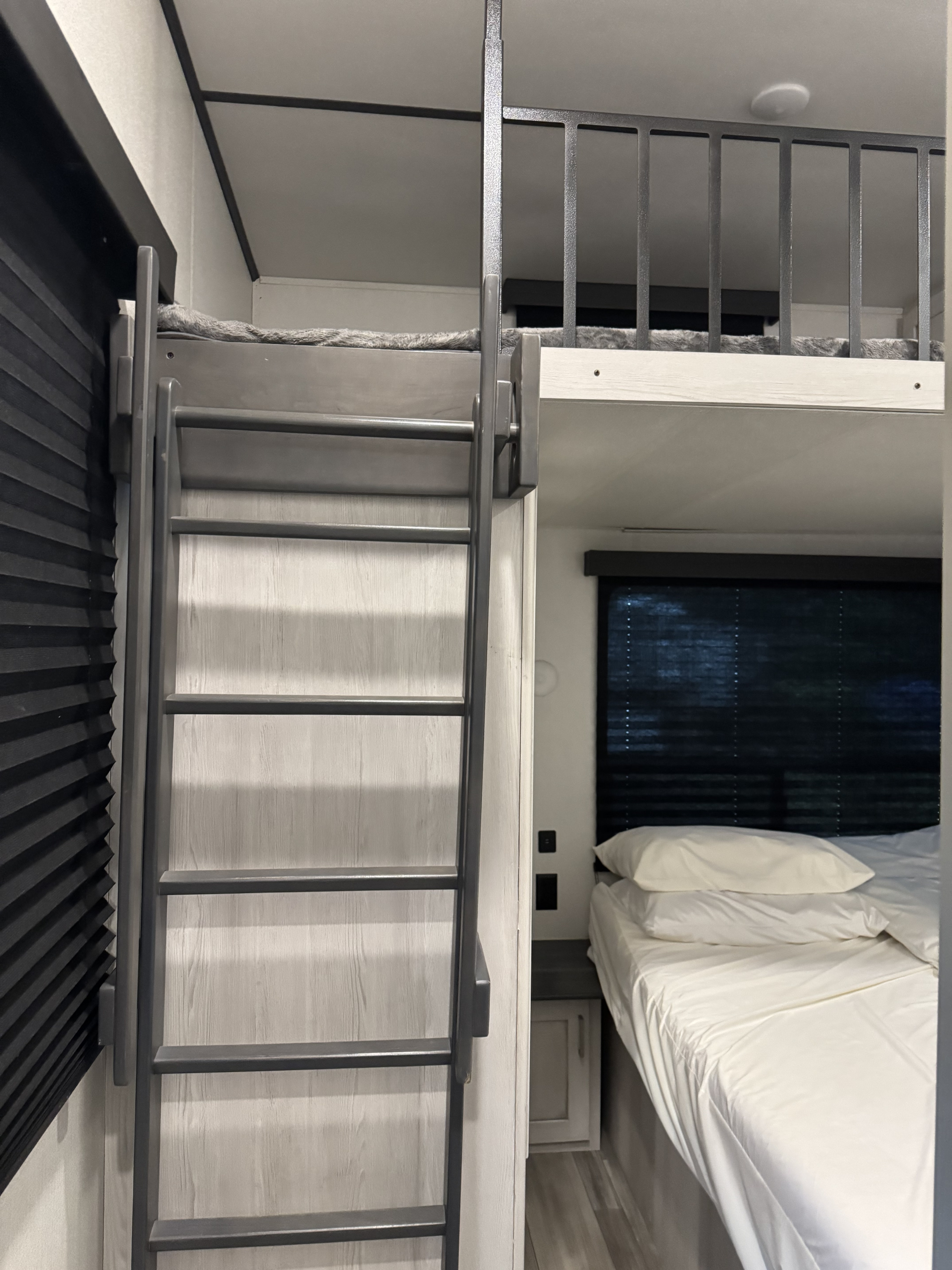 Compact RV rental sleeping area featuring a sturdy ladder to a top bunk and a neatly made lower bed.. Keystone Sprinter 2022