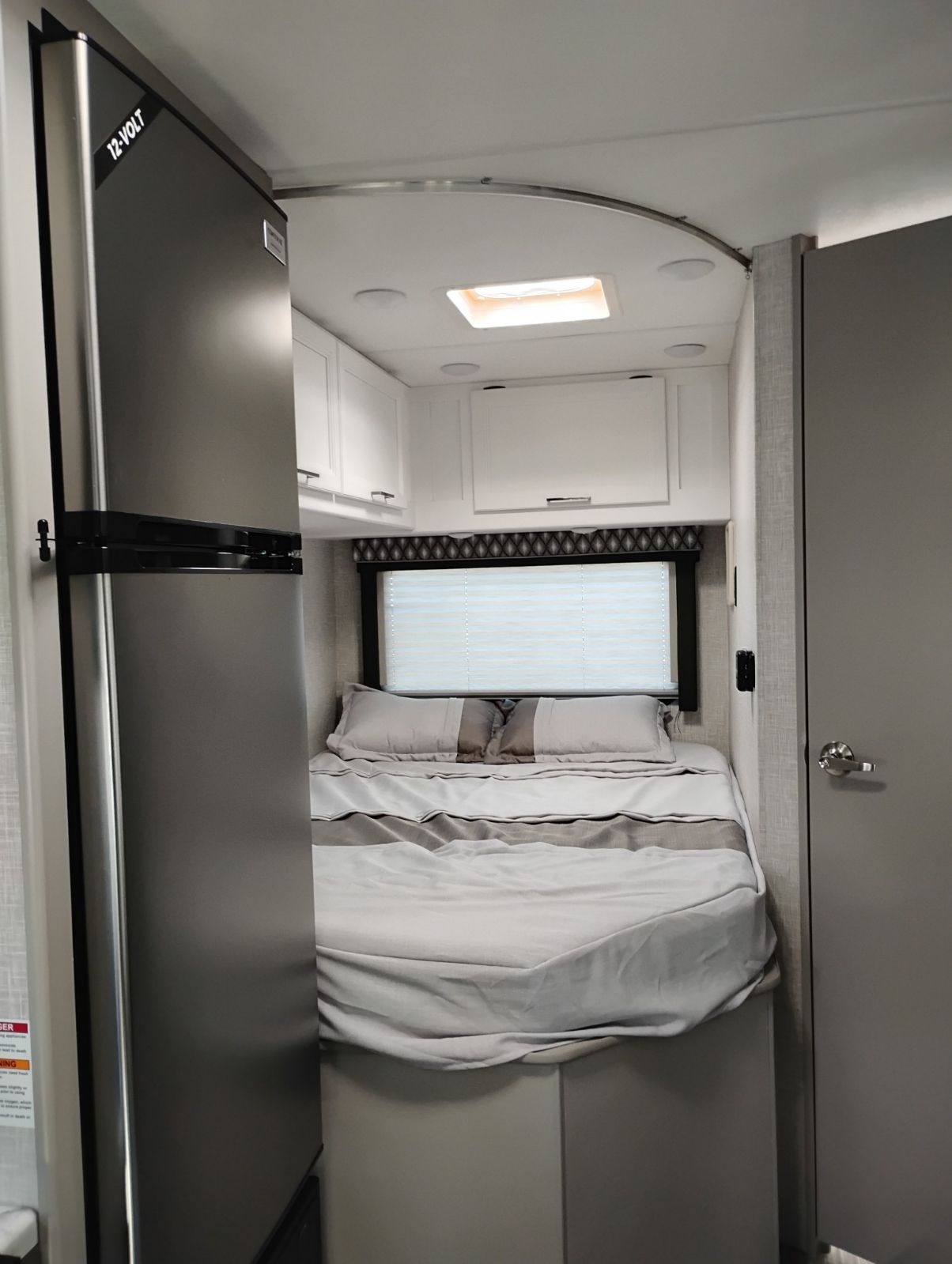 This RV rental features a cozy bedroom area with a compact bed, overhead storage, and a 12-volt refrigerator.. 1ha3gsc7xrn001469 Thor motor coach 2025