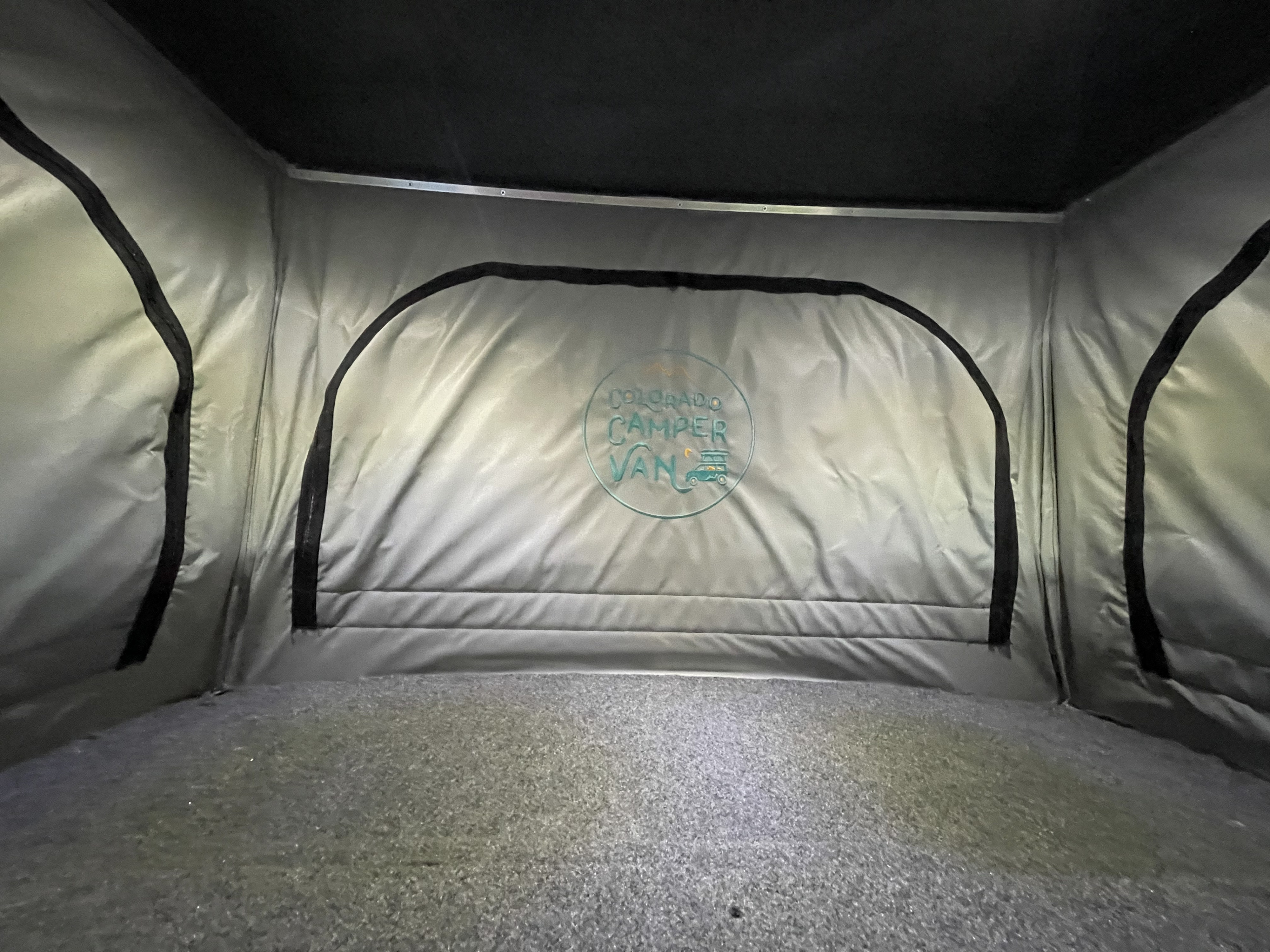 Interior of a Colorado Camper Van pop-top rv rental, showing the grey tent walls, carpeted floor, and brand logo.. Volkswagen Westfalia 1997