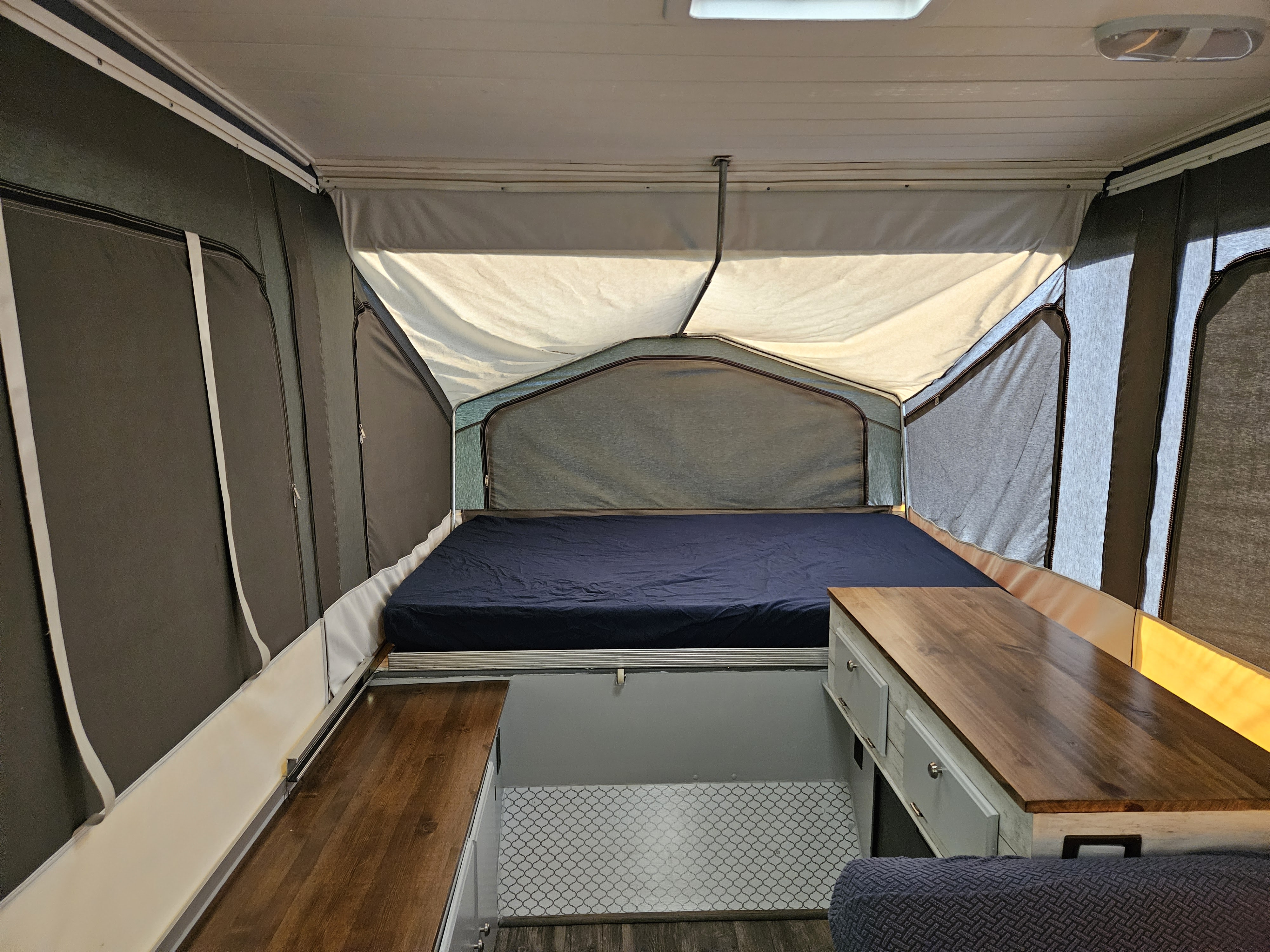 Cozy pop-up RV rental interior featuring a large bed, stylish wood countertops, and modern flooring for your travels.. Forest River Rockwood Freedom 1994