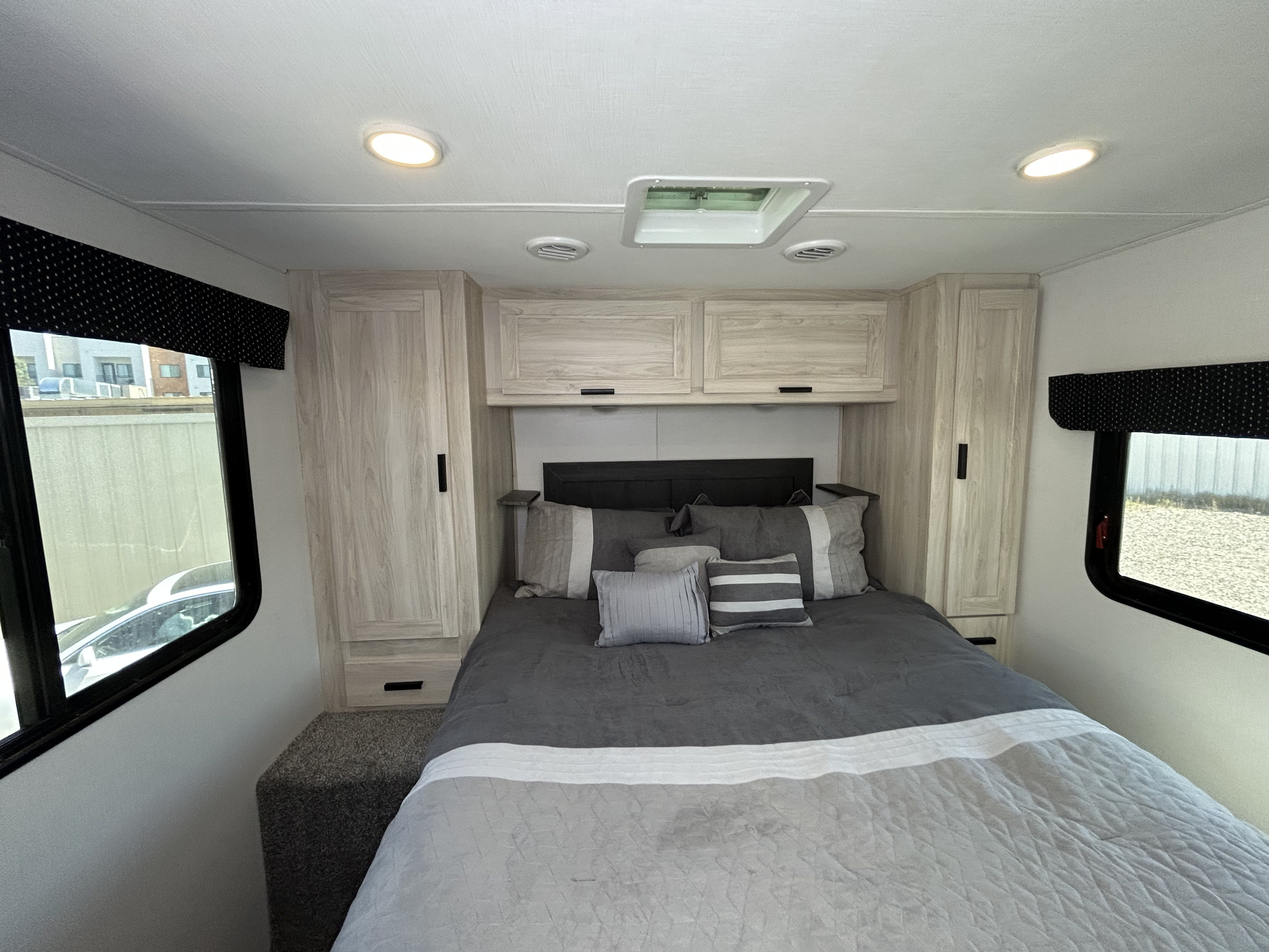This RV rental offers a comfortable bedroom featuring a queen bed, overhead storage, and dual windows for scenic views.. Forester LE 2023