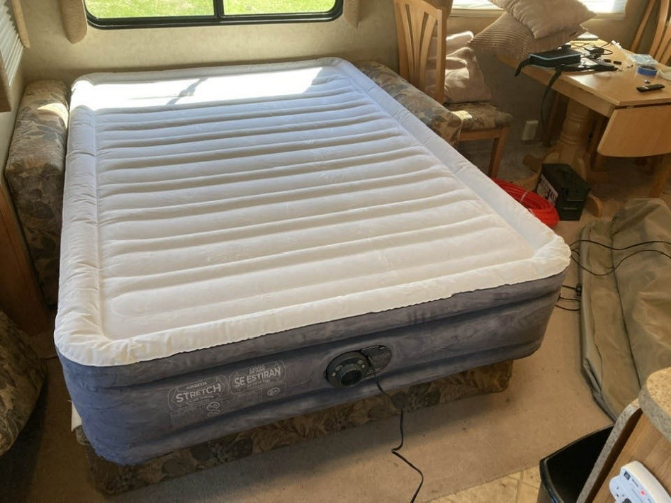 A large, fully inflated air mattress with a white top and gray base, set up as a comfortable bed in an RV rental interior.. Mckenzie Starwood LX 2008