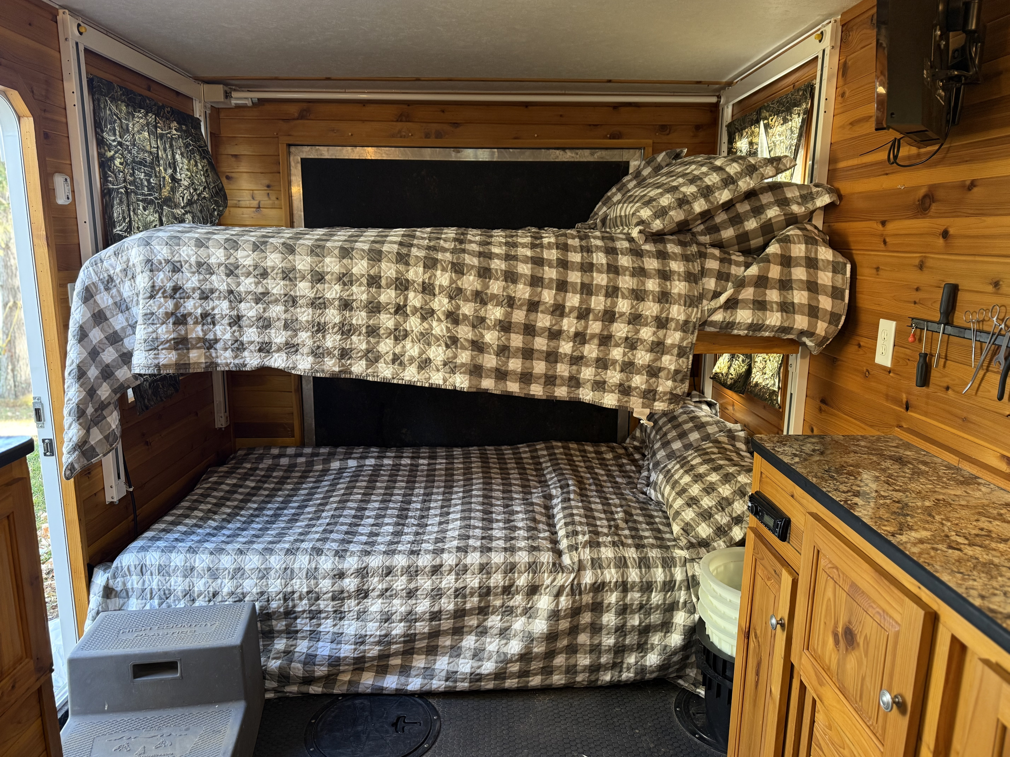 An RV rental interior with inviting bunk beds, classic plaid quilts, and warm wood accents. Great for camping trips.. Ice Castle Fish Houses Toy Hauler 2016