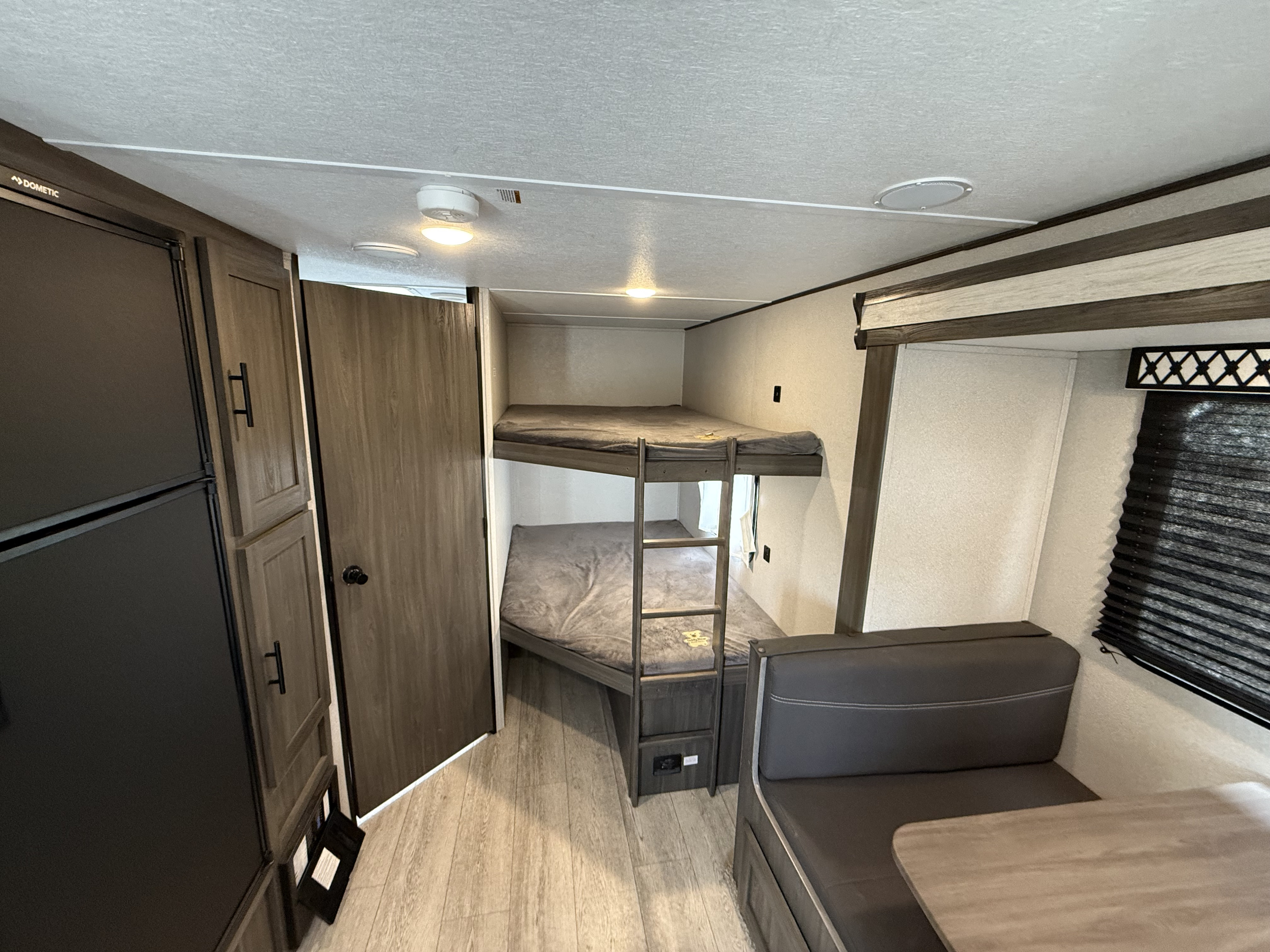An inviting RV rental interior, showing bunk beds, a dinette with dark seating, and sleek wood cabinetry.. Forest River Shasta 2021