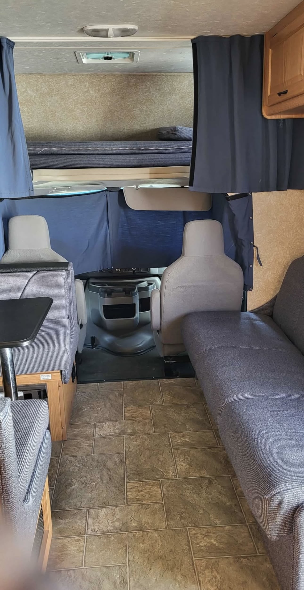 This RV rental interior shows a bunk bed, dinette, and sofa area with tiled flooring and privacy curtains.. Four Winds Majestic 2011