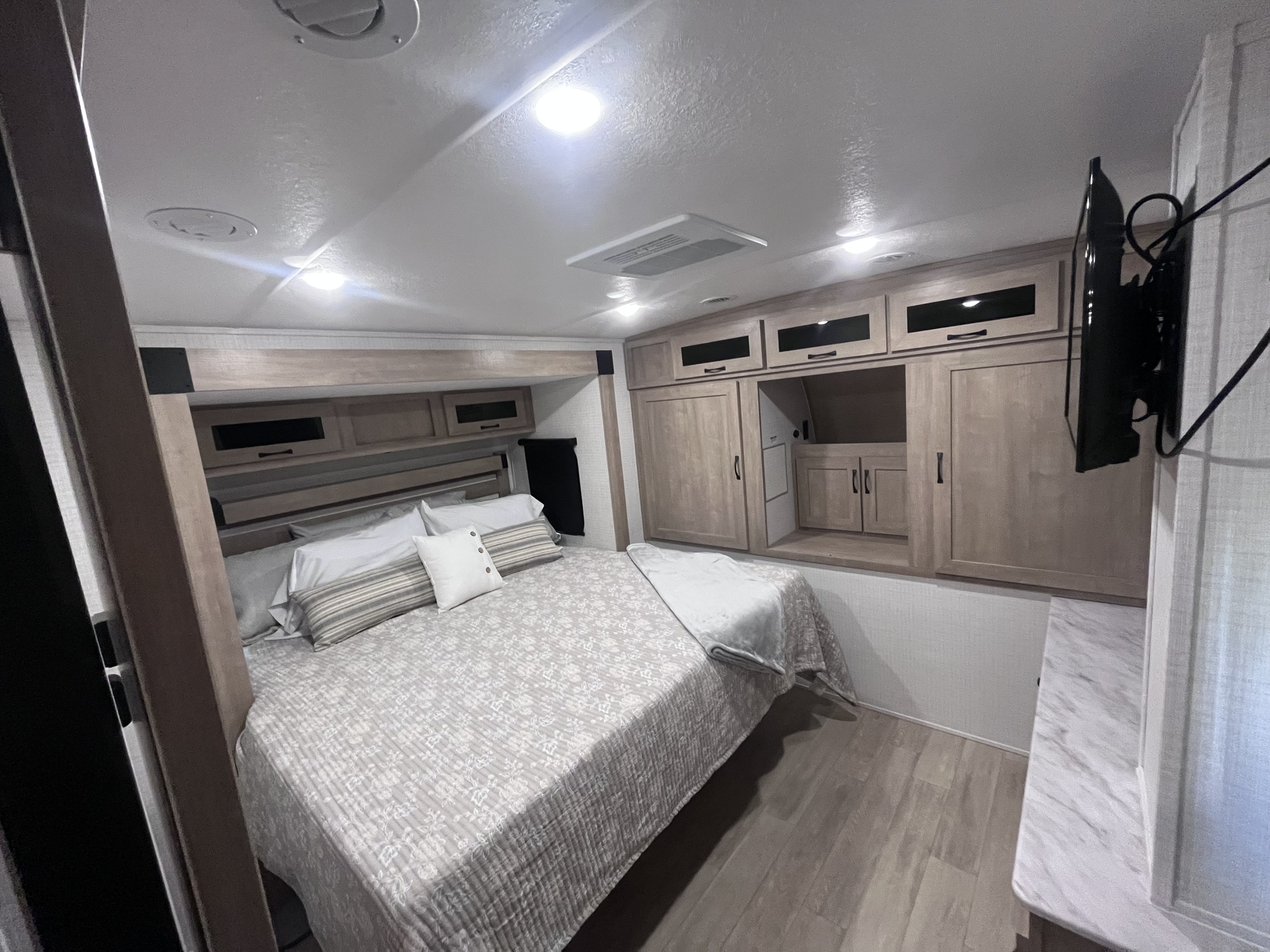 RV rental master bedroom showcasing a cozy bed, integrated storage cabinets, and a flat-screen TV.. Forest river 306RKTS Palomino 2025