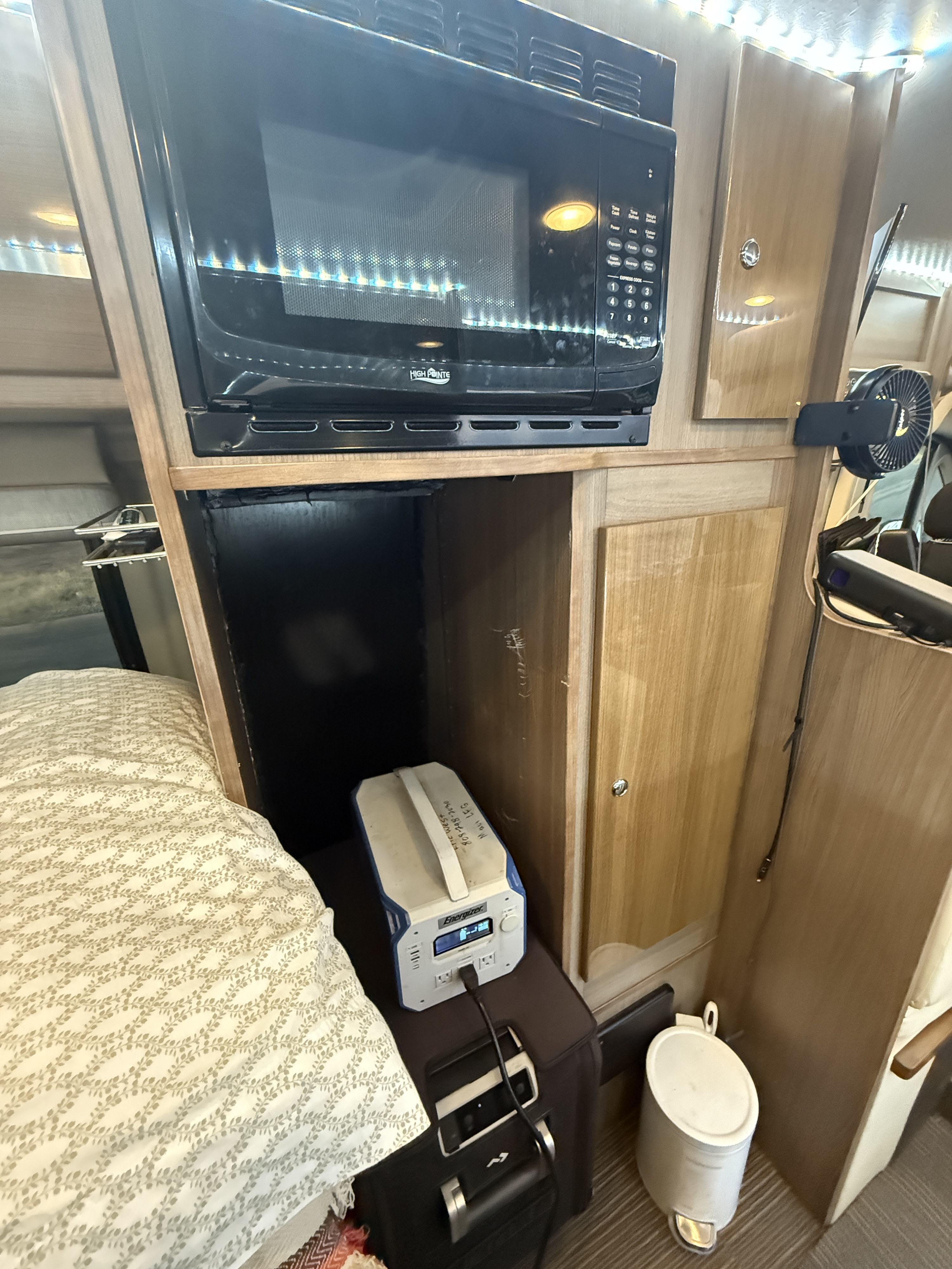 RV rental interior: A compact space with a microwave, cozy bed, and portable power station, highlighting practical amenities.. Winnebago Travato 2016