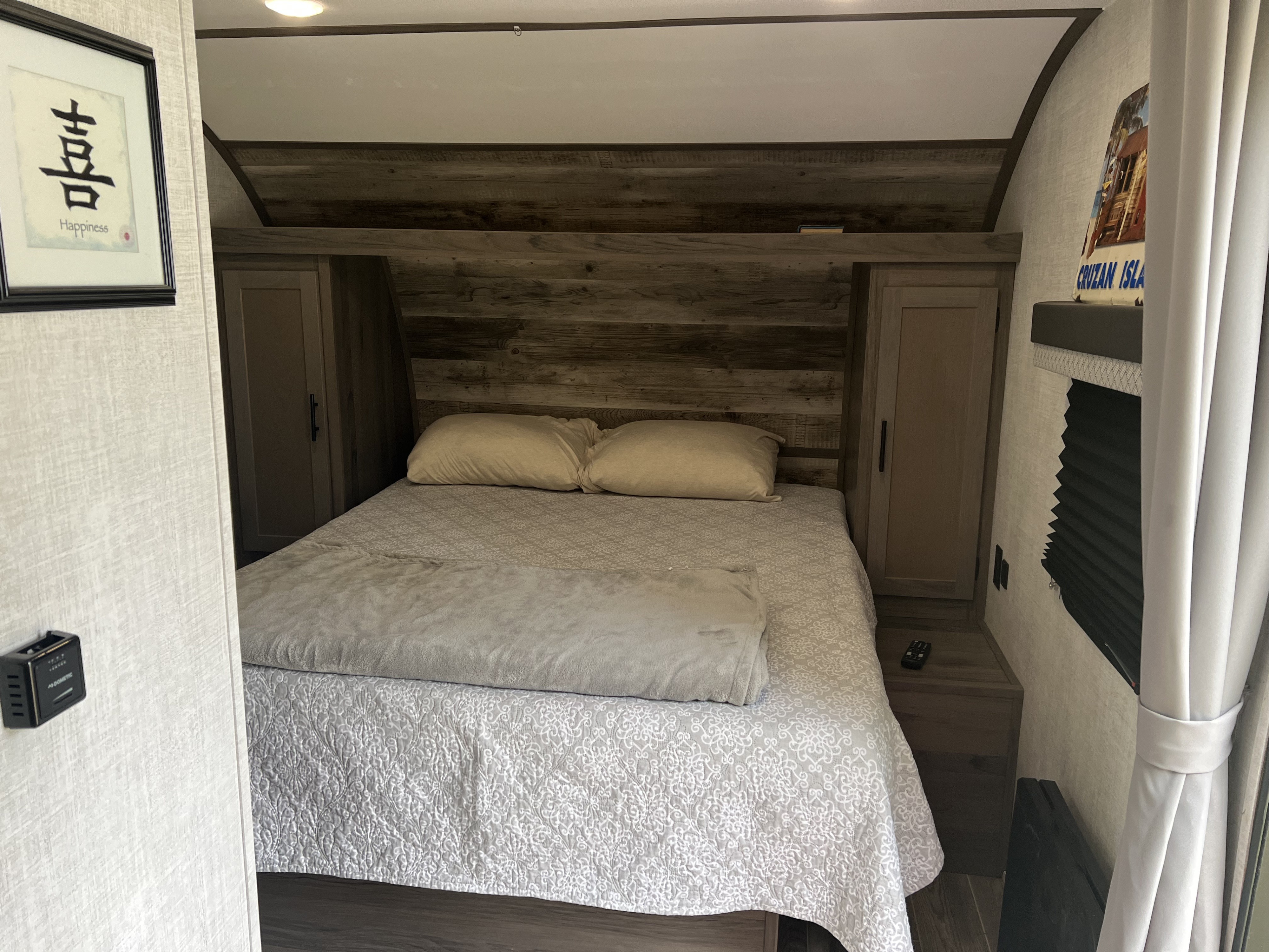 Cozy RV rental bedroom features a comfortable queen bed with rustic wood headboard and built-in storage.. Gulf Stream Ameri-Lite 2022