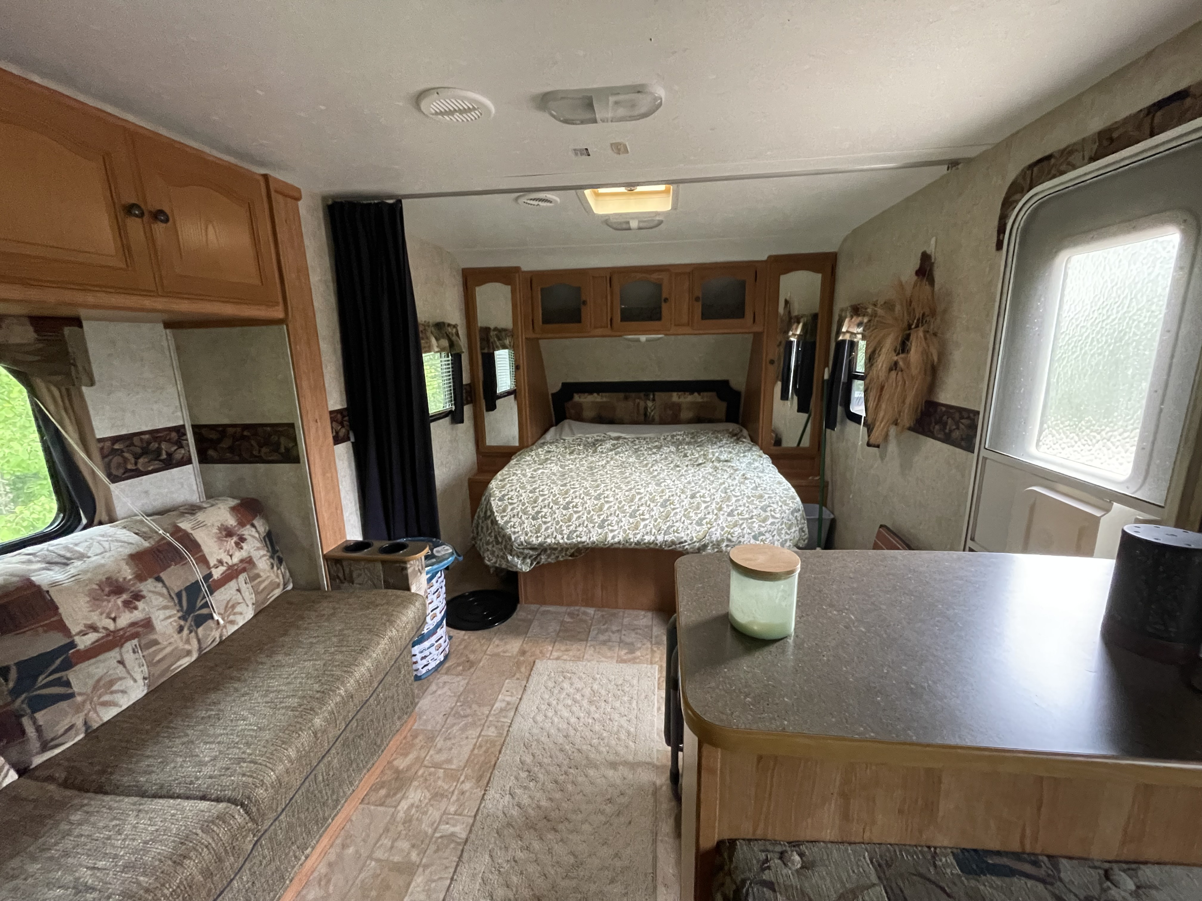 Inside this spacious RV rental, a cozy bedroom with bed, cabinets, and dining area with seating offers comfortable travel.. Keystone RV Passport 2008