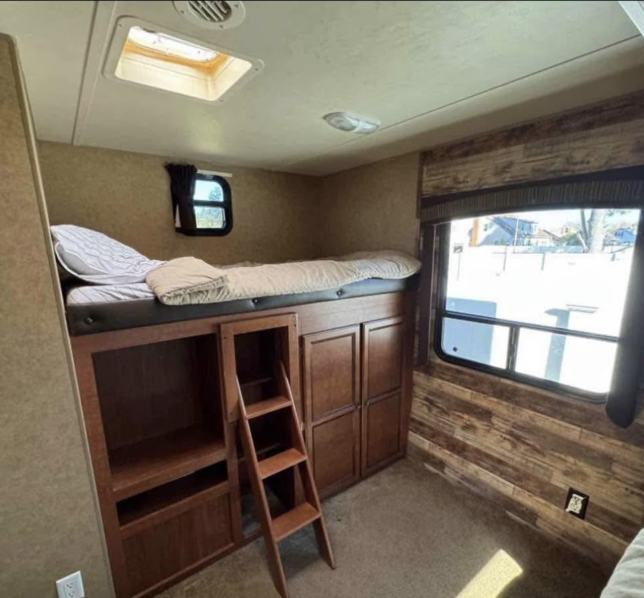 Inside an RV rental: a bunk bed with ladder, built-in storage, and a large window showing a snowy view. Comfy camper living.. Jayco Jay Flight 2013