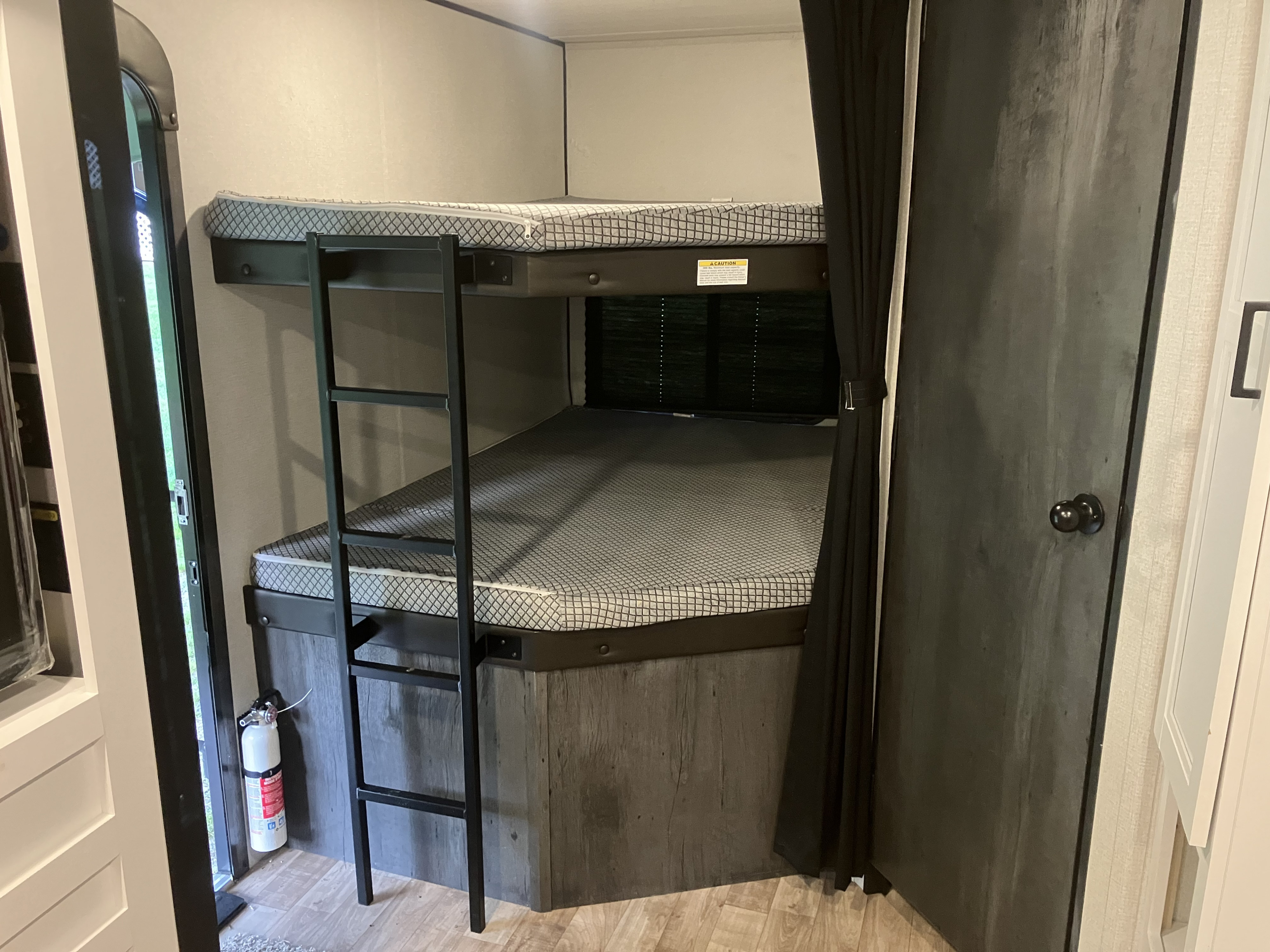 RV rental interior: cozy bunk beds with a ladder, privacy curtain, and fire extinguisher, ready for adventure.. Keystone RV Hideout 2022