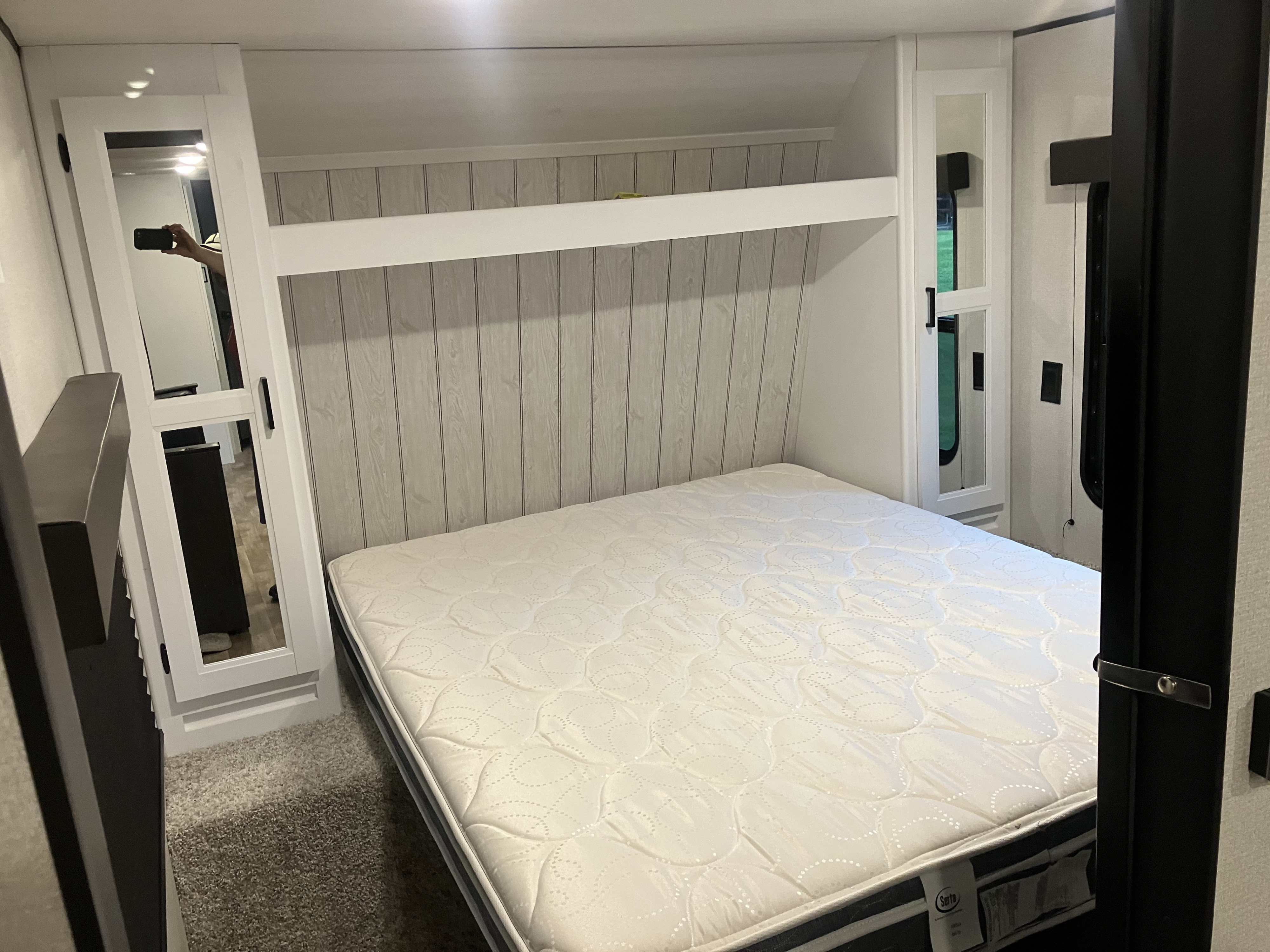 RV rental bedroom: A comfortable bed with overhead storage and mirrored cabinets in a compact space.. Keystone RV Hideout 2022